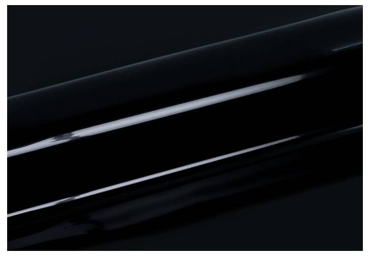 Ein glänzendes schwarzes zylindrisches Objekt mit reflektierender Oberfläche, diagonal gegen einen dunklen Hintergrund positioniert.