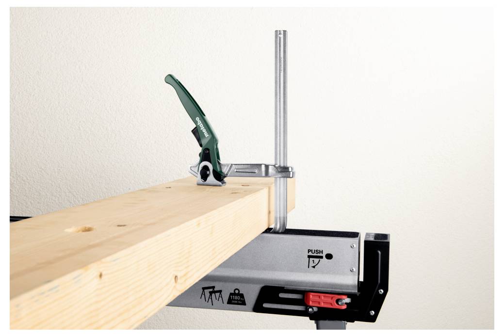 Ein Holzbalken, der sicher auf einer Werkbank eingespannt ist und durch eine grüne Griffspannzwinge an Ort und Stelle gehalten wird, demonstriert einen stabilen Aufbau für die Holzbearbeitung.