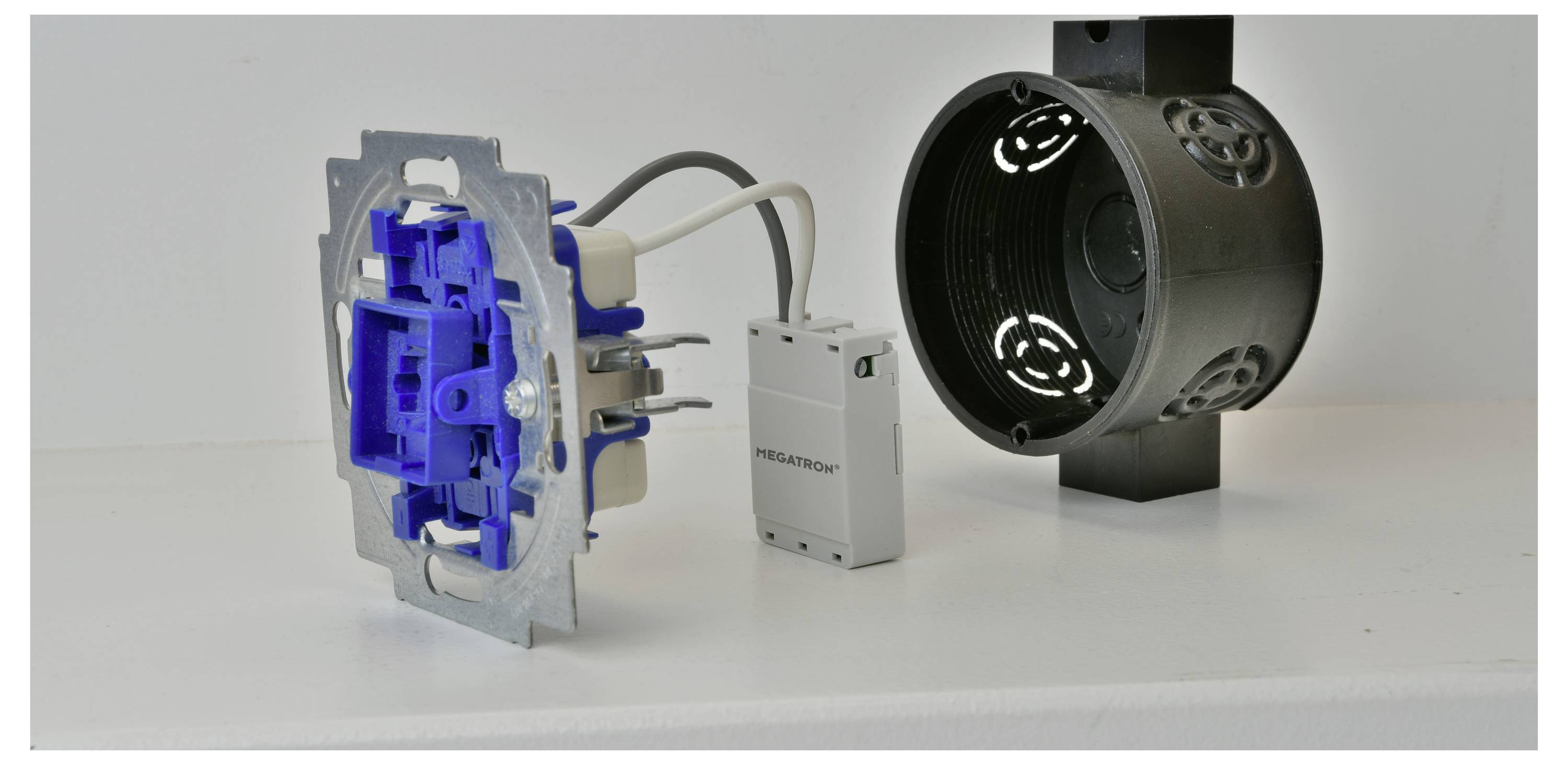 Dieses Bild zeigt eine zerlegte Schaltkomponente mit blauem Gehäuse und einem zylindrischen Montagekasten auf einer weißen Oberfläche.