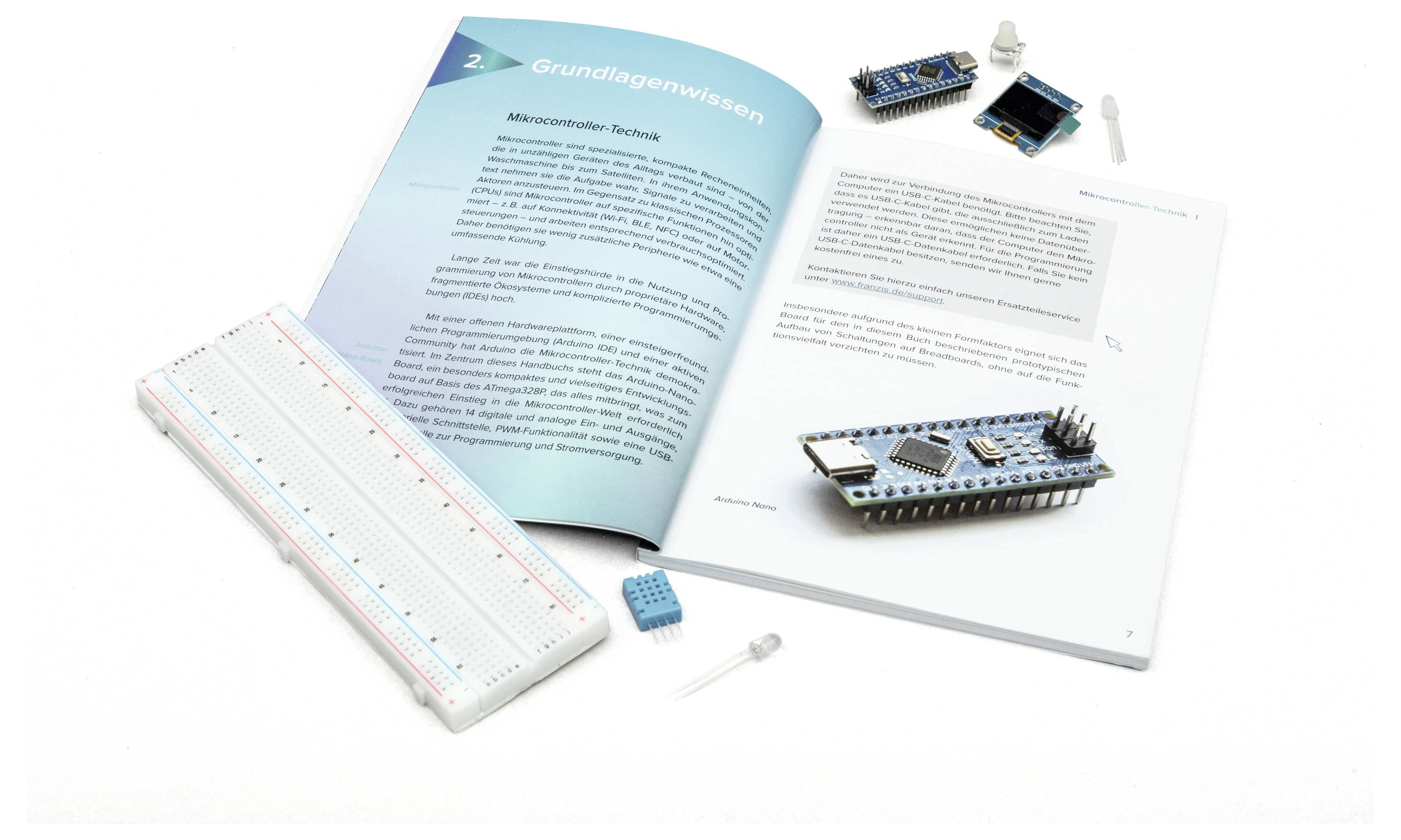 Aufgeschlagenes Buch über Mikrocontroller-Grundlagen mit einem Steckbrett, Mikrocontroller, LED und anderen Komponenten daneben, das ein Elektronik-Projektaufbau illustriert.
