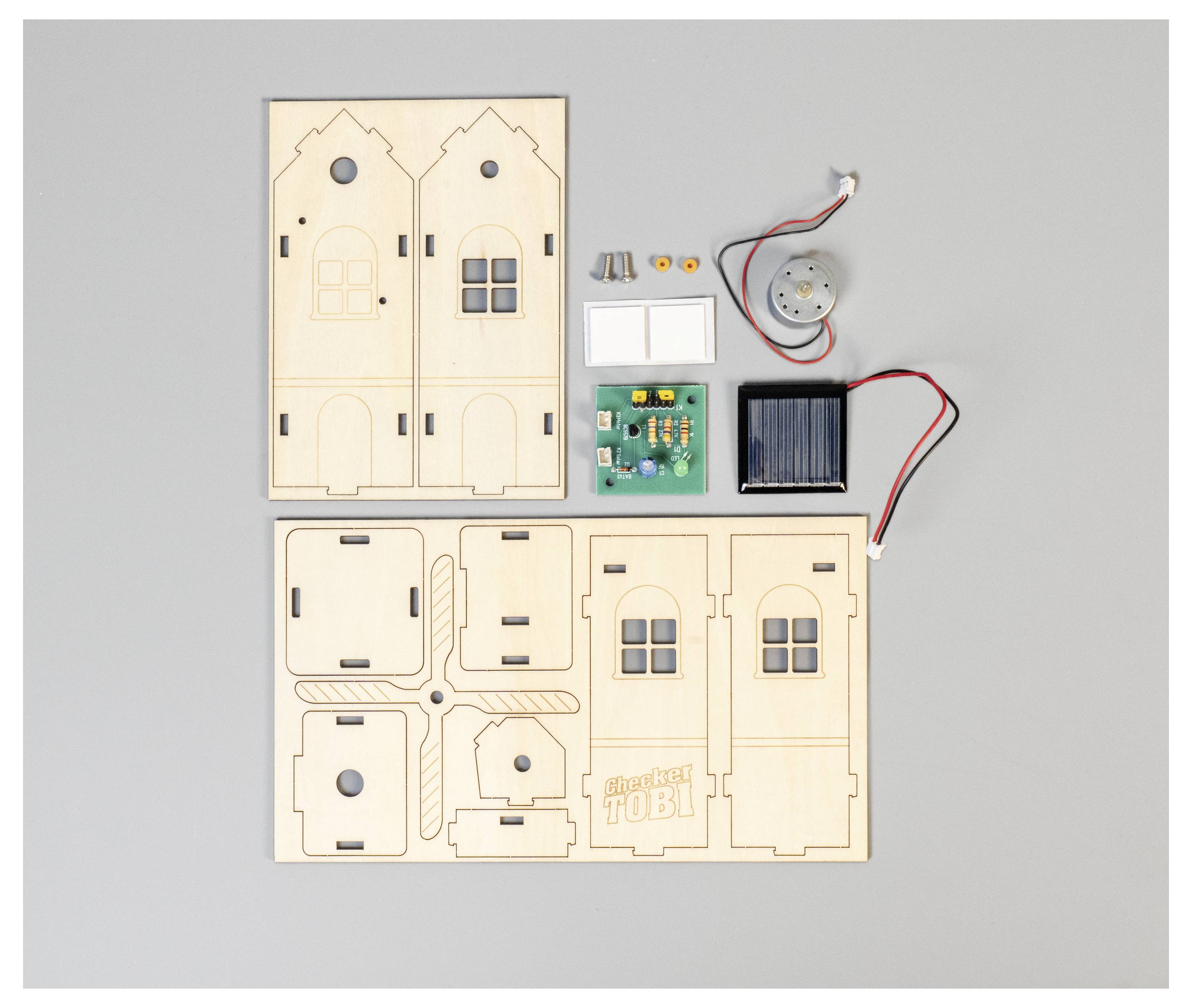 Holzbausatz-Komponenten, einschließlich Paneele mit Ausschnitten für Tür und Fenster, elektronische Teile und Verdrahtung zum Zusammenbau eines kleinen Modellgebäudes.