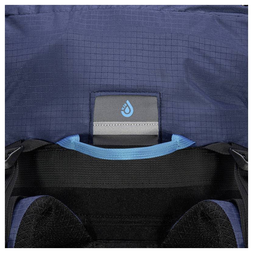 Nahaufnahme der Rückseite eines Rucksacks mit blauem Stoff mit gewebter Textur und einem kleinen Logo mit einem Handsymbol in der Mitte oben.