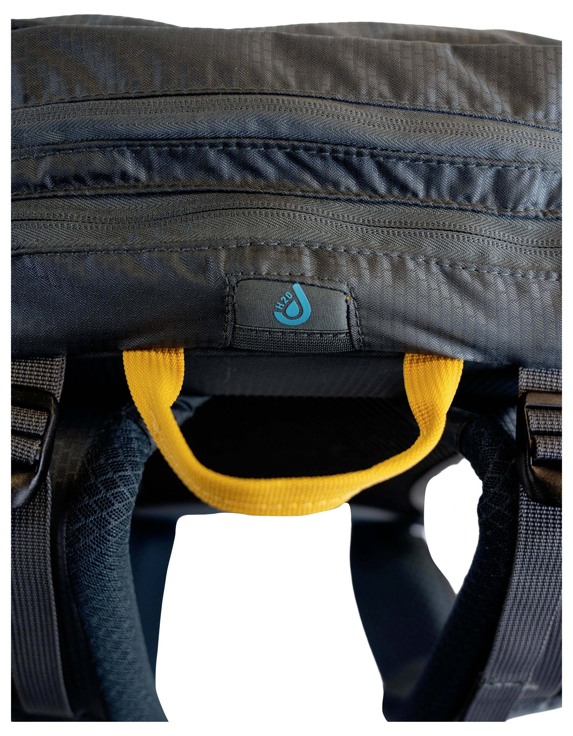 Rucksack von oben gezeigt mit schwarzen Reißverschlüssen und einem kleinen blauen Logo, mit einem gelben Griff zum einfachen Tragen.