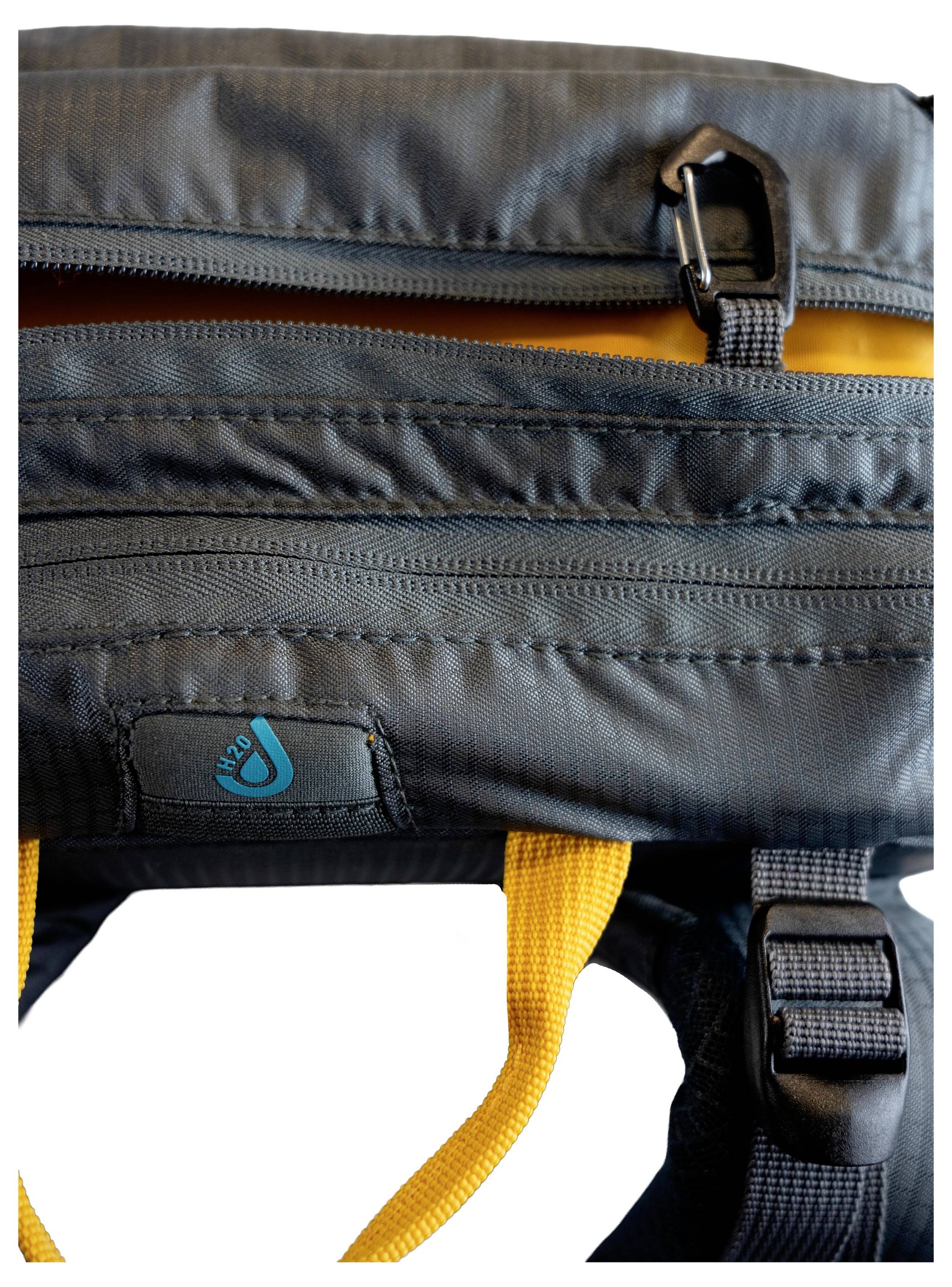 Ein schwarzer Rucksack mit einem orangefarbenen Griff und einem blauen Logo, das dem Betrachter zugewandt ist, zeigt eine Nahaufnahme des oberen Bereichs.