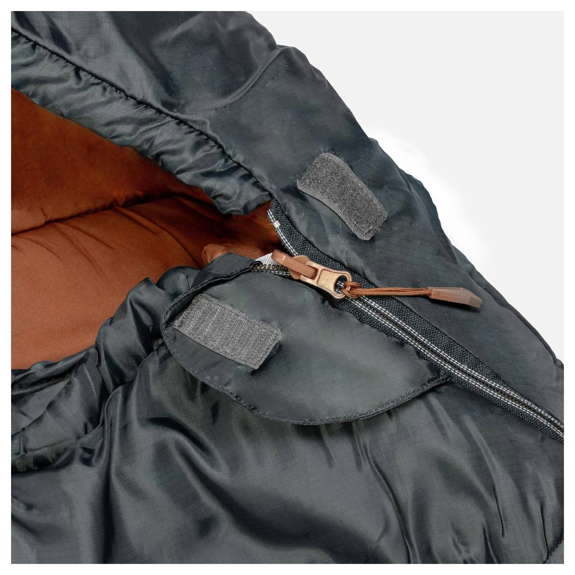 Eine Nahaufnahme eines dunklen Nylon-Schlafsacks mit seinem Reißverschluss und einer Kapuze mit weichem braunem Innenfutter, die die Wärme und den Komfort des Schlafsacks hervorhebt.