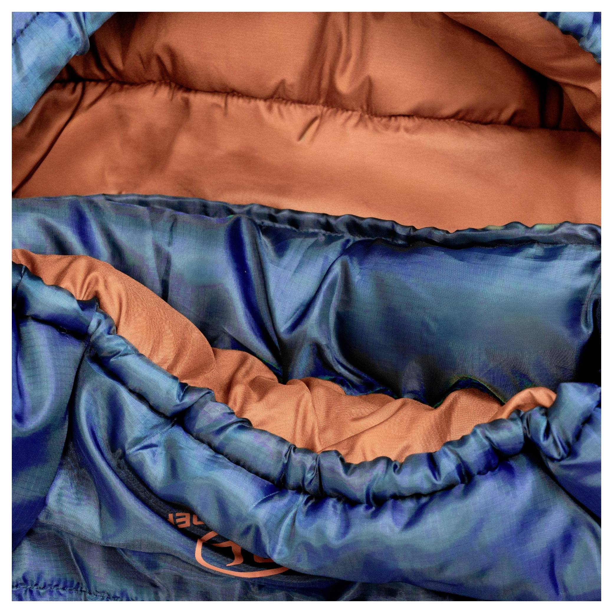 Eine Nahaufnahme eines blau und orange gefärbten Schlafsacks, die das innere Futter und die raffinierten Kanten zeigt und seine Wärme und kompaktes Design hervorhebt.