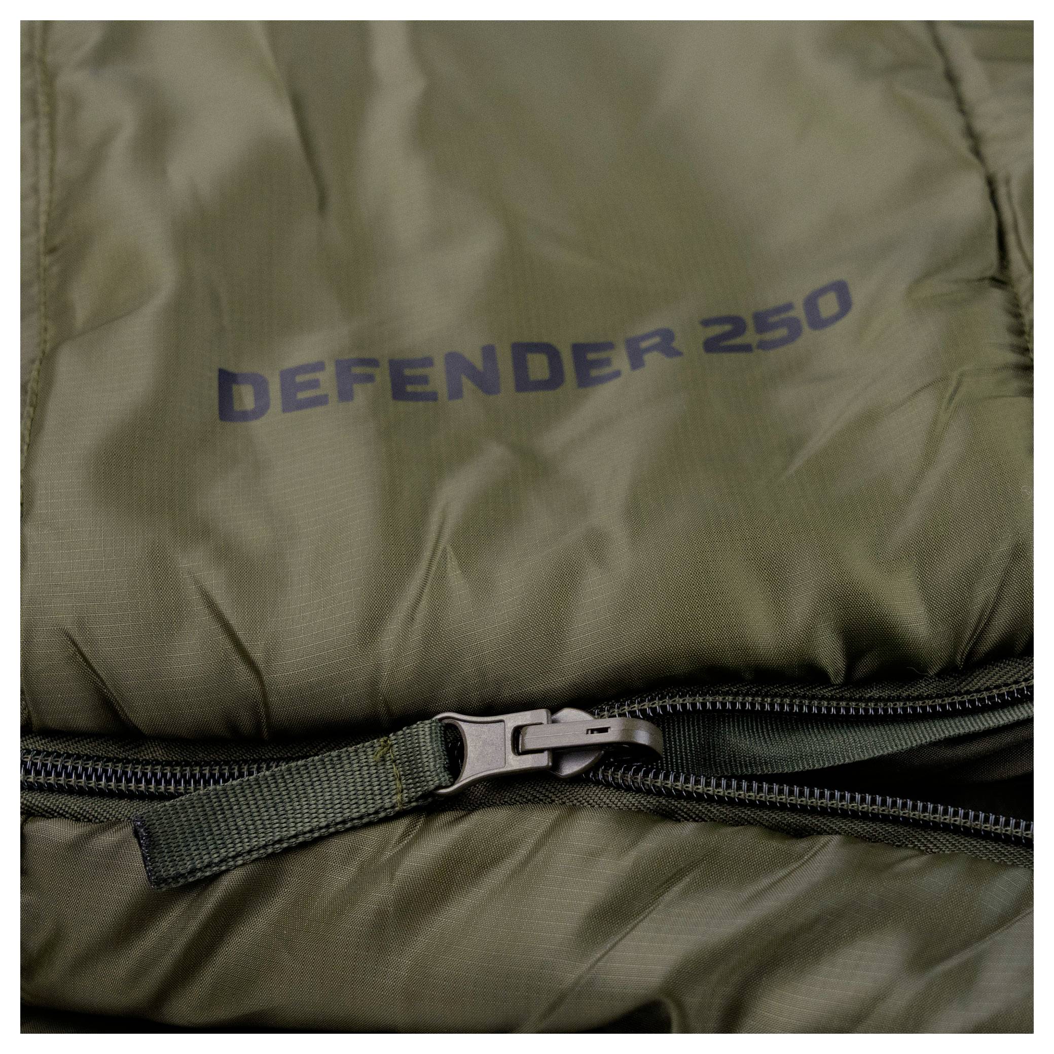 Eine Nahaufnahme eines grünen Schlafsacks mit teilweise geöffnetem Reißverschluss. Der Text „DEFENDER 250