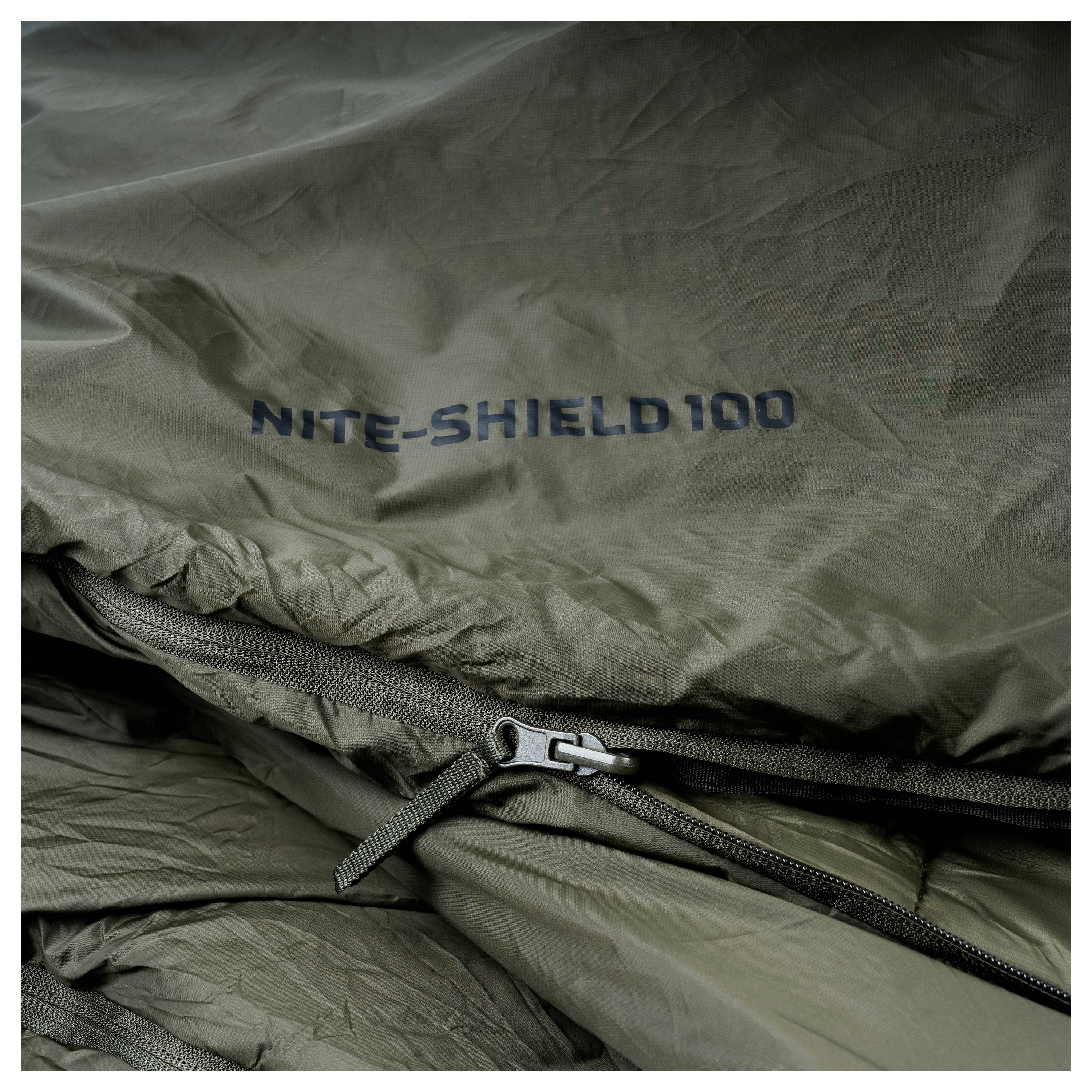 Ein Schlafsack aus dunkelgrünem Stoff mit einem Reißverschluss und dem aufgedruckten Text „NITE-SHIELD 100