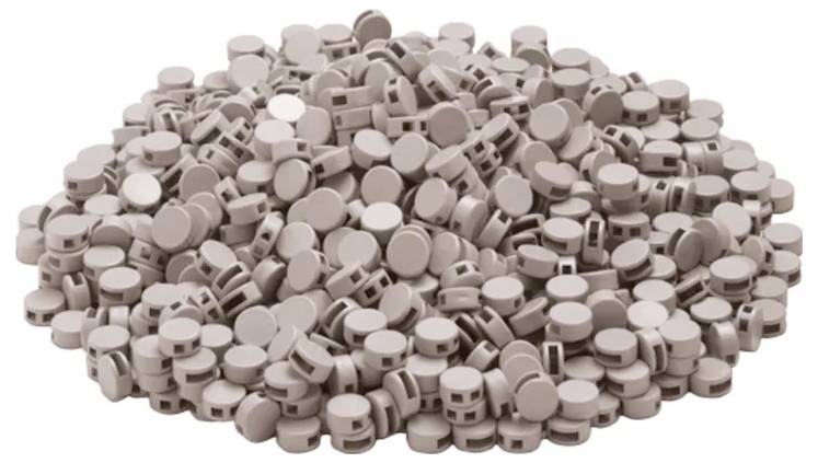 Ein großer Stapel brauner zylindrischer Tabletten mit Rillen ist zusammengestapelt.