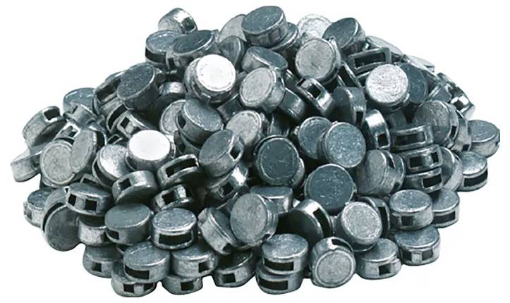 Ein Haufen metallischer Pellets, kreisförmig mit glänzenden Oberflächen. Sie sind in einem ungleichmäßigen Haufen gestapelt und ähneln Industriekomponenten.