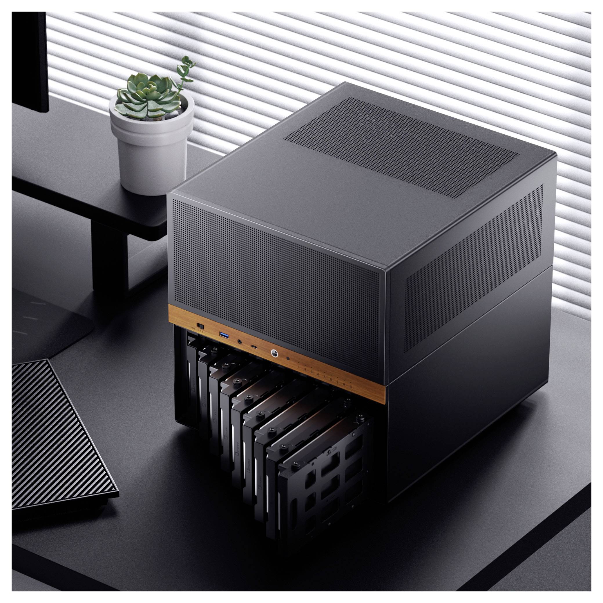 Ein eleganter schwarzer Computer-Server mit mehreren abnehmbaren Festplattenschächten auf einem modernen Schreibtisch, neben einer Tastatur und einer kleinen Pflanze.