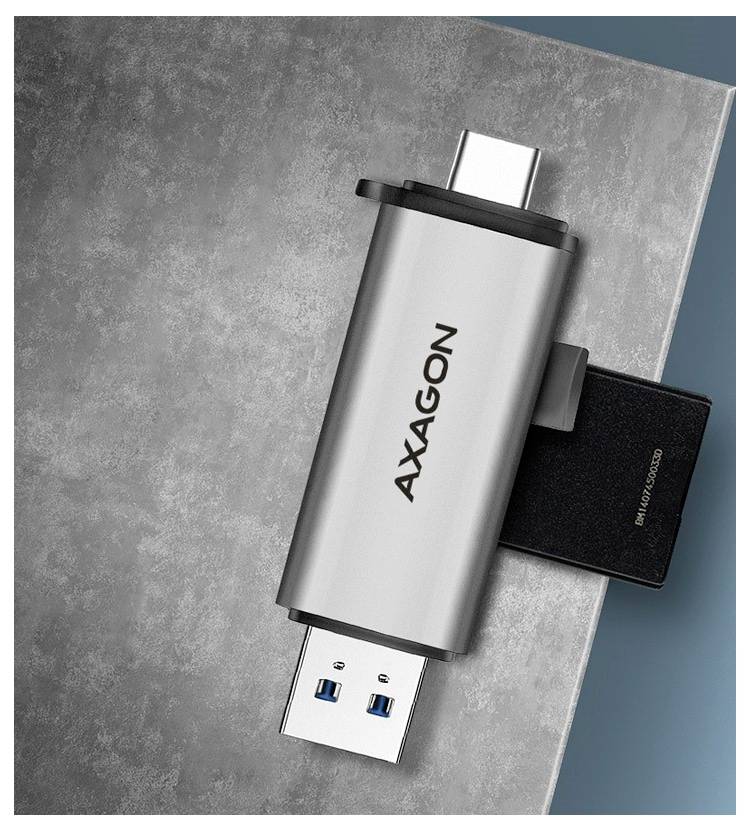 Silber AXAGON USB-Stick mit Doppelsteckern auf einer grauen Oberfläche gezeigt, mit einer schwarzen Kappe an einem Ende angebracht.