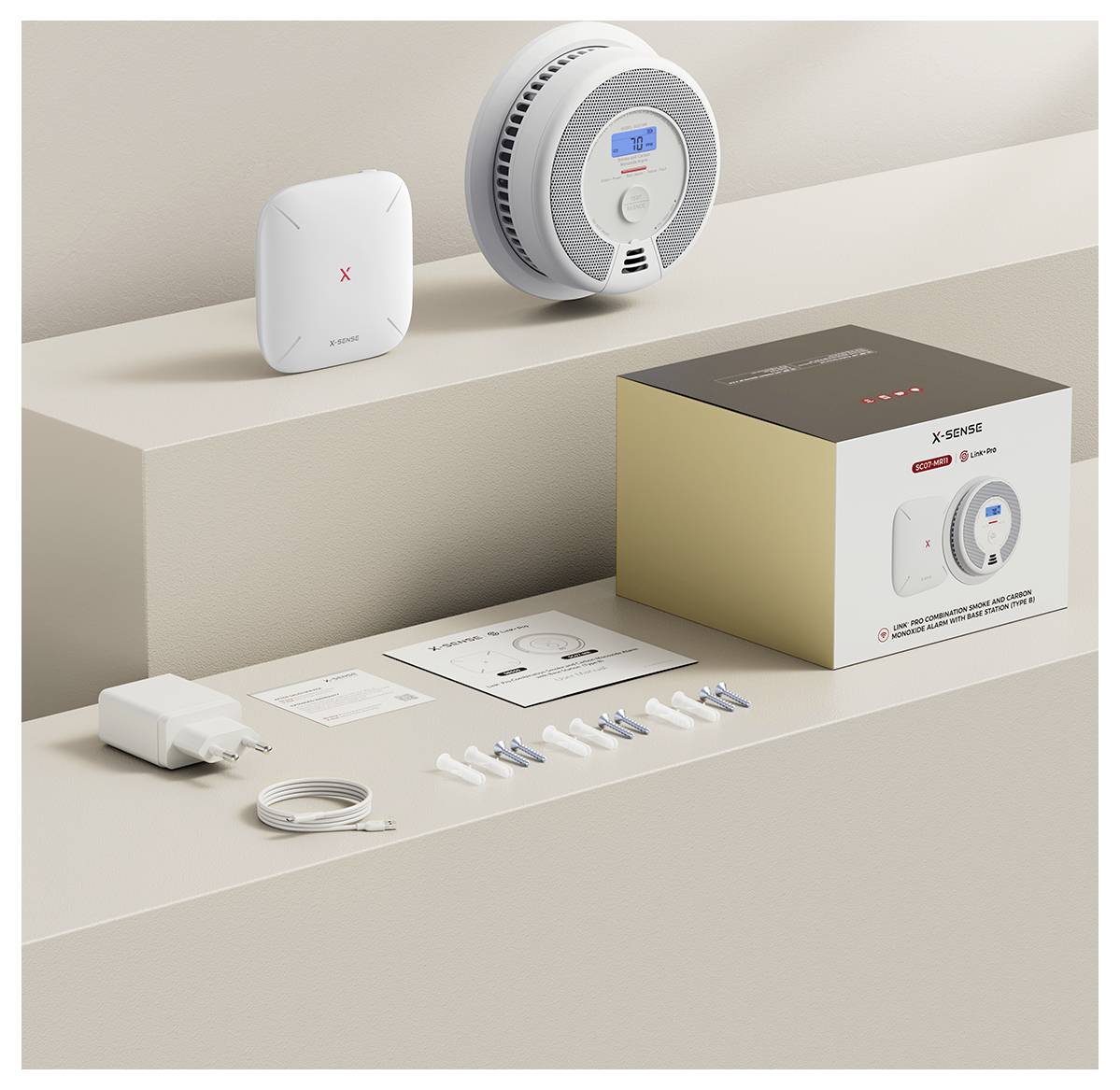 Ein Rauchmelder-Set mit einem weißen Rauchmelder, Befestigungsmaterial, Kabel, Adapter, Gebrauchsanweisung und Verpackung auf einem Tisch.