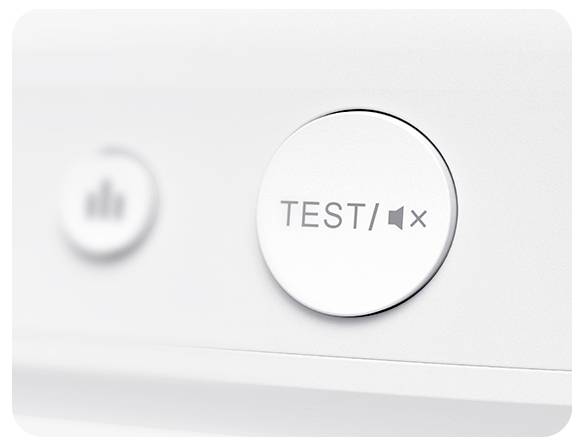 Nahaufnahme eines weißen Knopfes mit der Aufschrift 'TEST/MUTE' auf einem elektronischen Gerät. Ein weiterer Knopf ist verschwommen im Hintergrund.