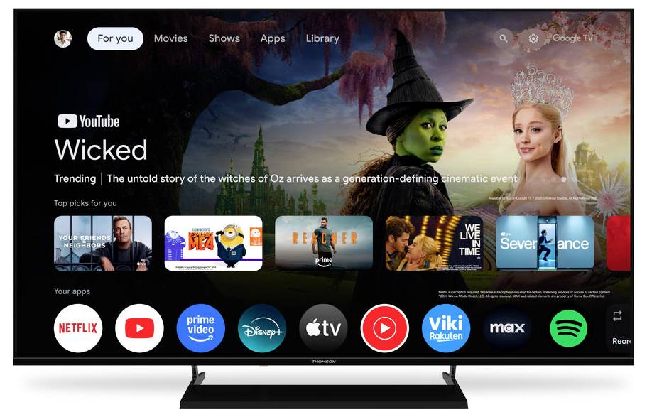 Ein Smart-TV-Interface zeigt ein Menü mit Streaming-Apps wie Netflix, Prime Video, Disney+ und YouTube an. Der hervorgehobene Bereich bewirbt „Wicked
