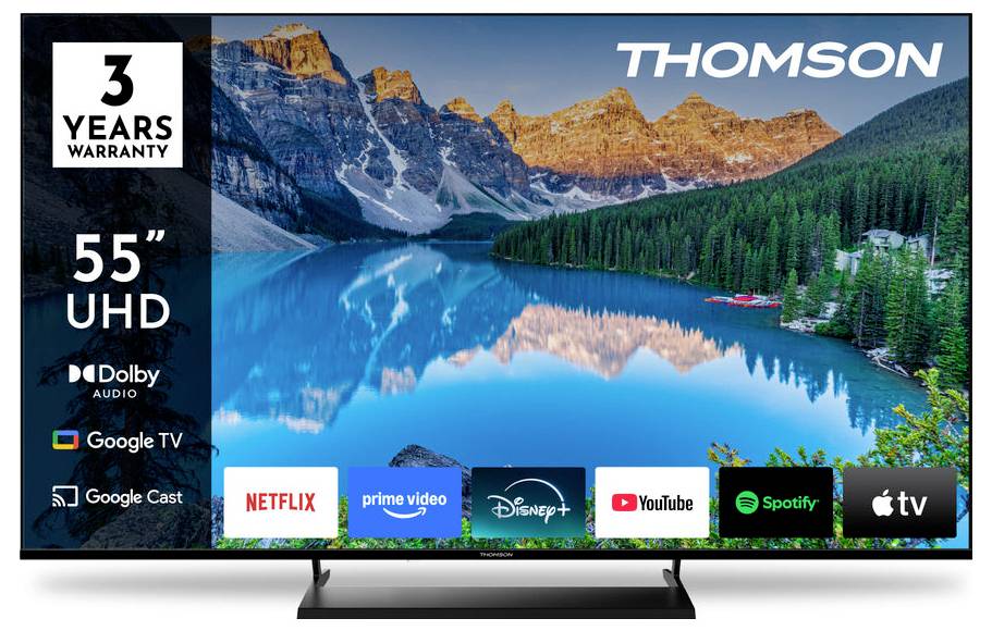 Ein Thomson 55-Zoll-UHD-Fernseher zeigt eine Bergseenlandschaft. Zu den Funktionen gehören 3 Jahre Garantie, Dolby Audio, Google TV mit App-Symbolen wie Netflix und YouTube.