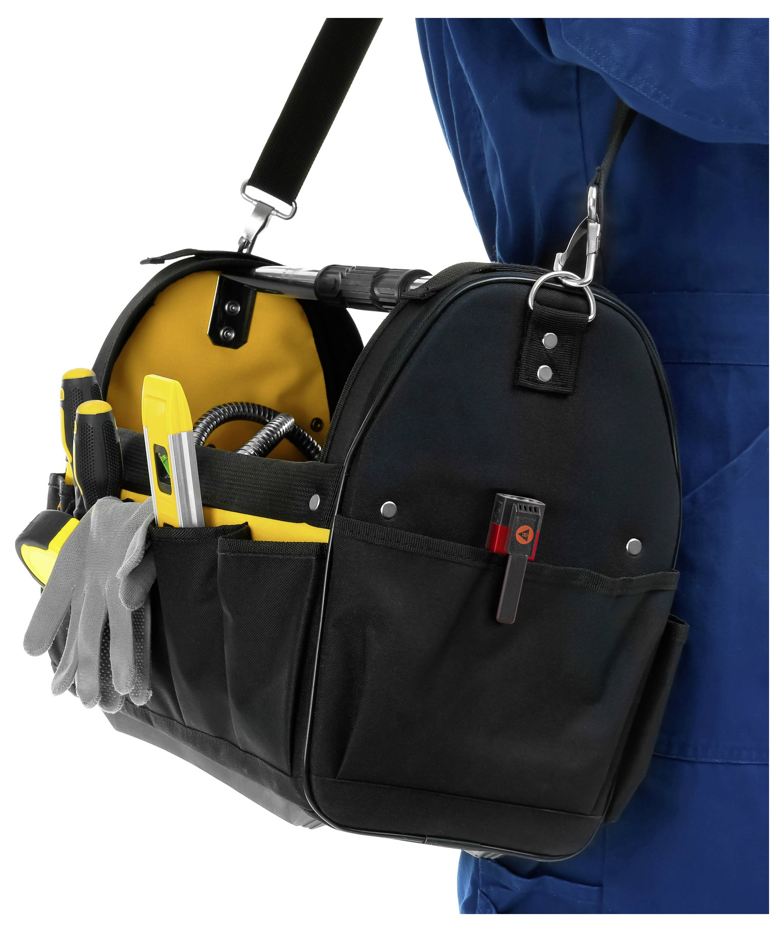 Techniker, der eine schwarze Werkzeugtasche mit gelbem Inneren und Handwerkzeugen trägt, die an einem Schultergurt über einem weißen Hintergrund hängt.