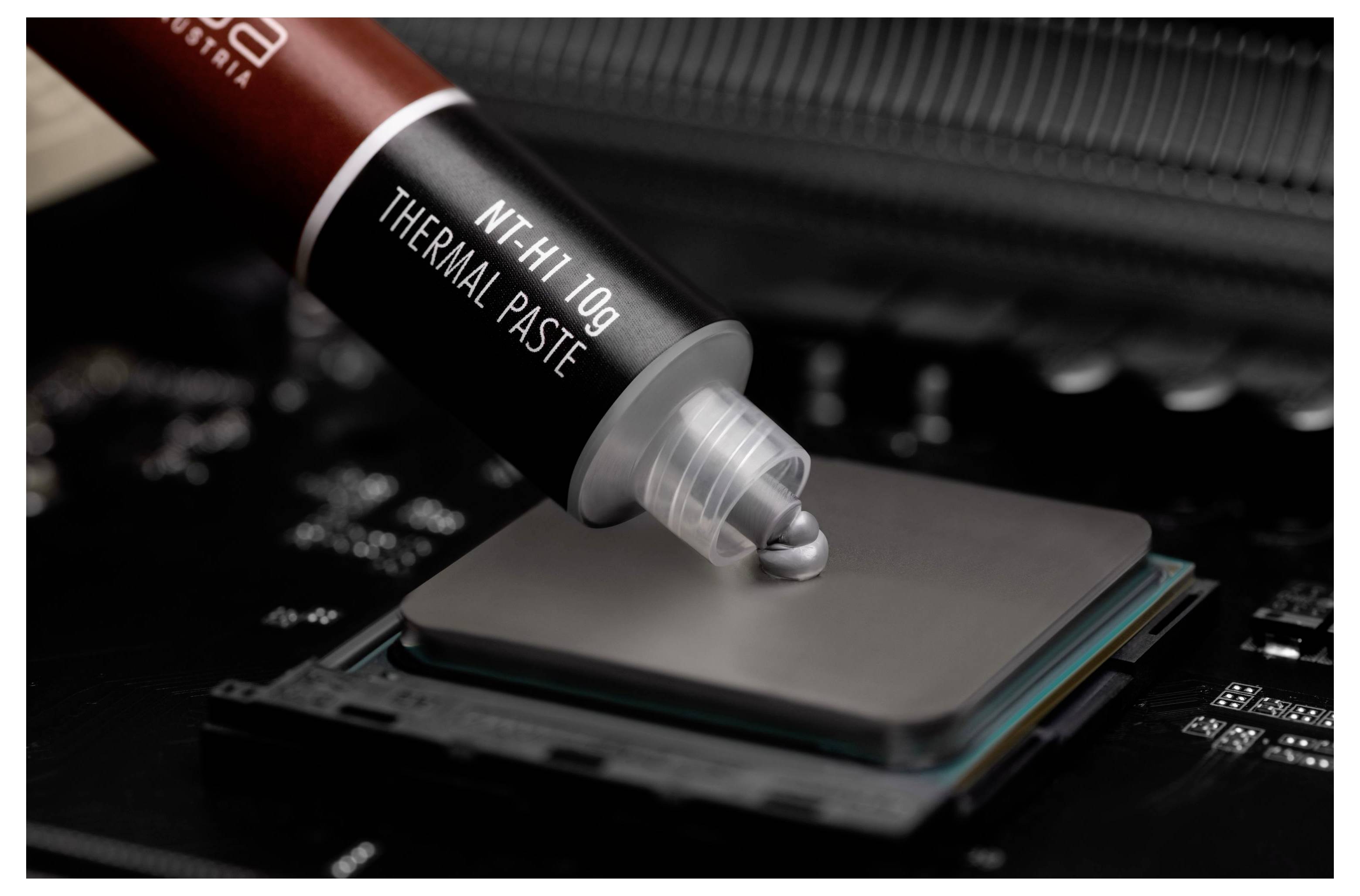 Wärmepaste wird aus einer Spritze auf einen Computerprozessor auf einem Motherboard aufgetragen.