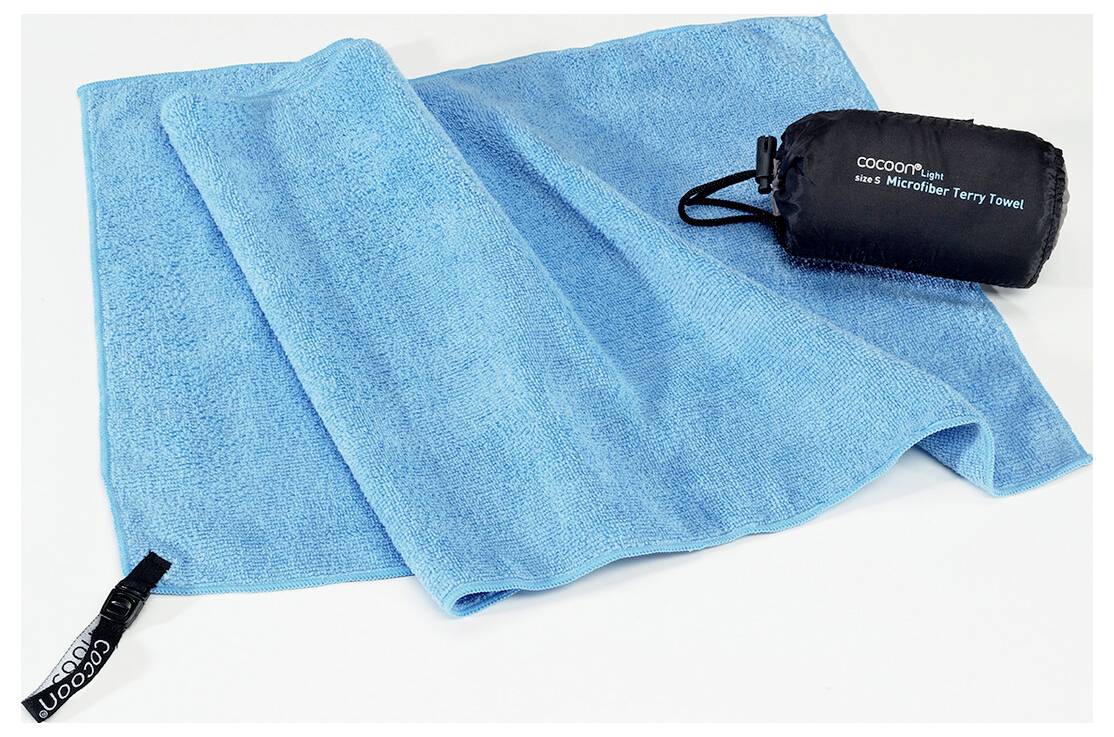 Ein hell blauес Mikrofaser-Handtuch liegt flach neben seiner kompakten schwarzen Aufbewahrungstasche, die mit dem Markennamen und dem Produkttyp beschriftet ist.