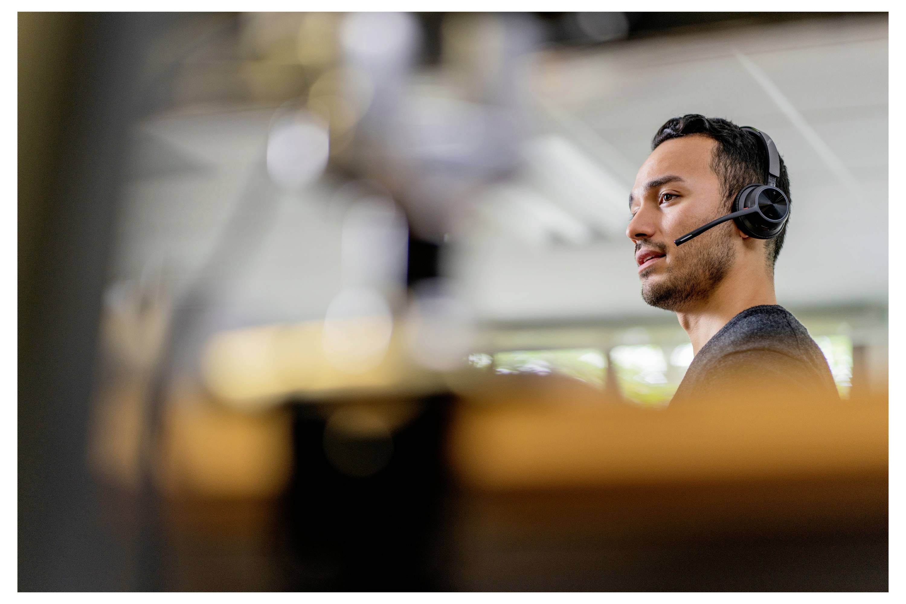 Eine Person, die ein Headset trägt, ist in ein Gespräch vertieft, mit einem unscharfen Hintergrund einer Innenraumkulisse.