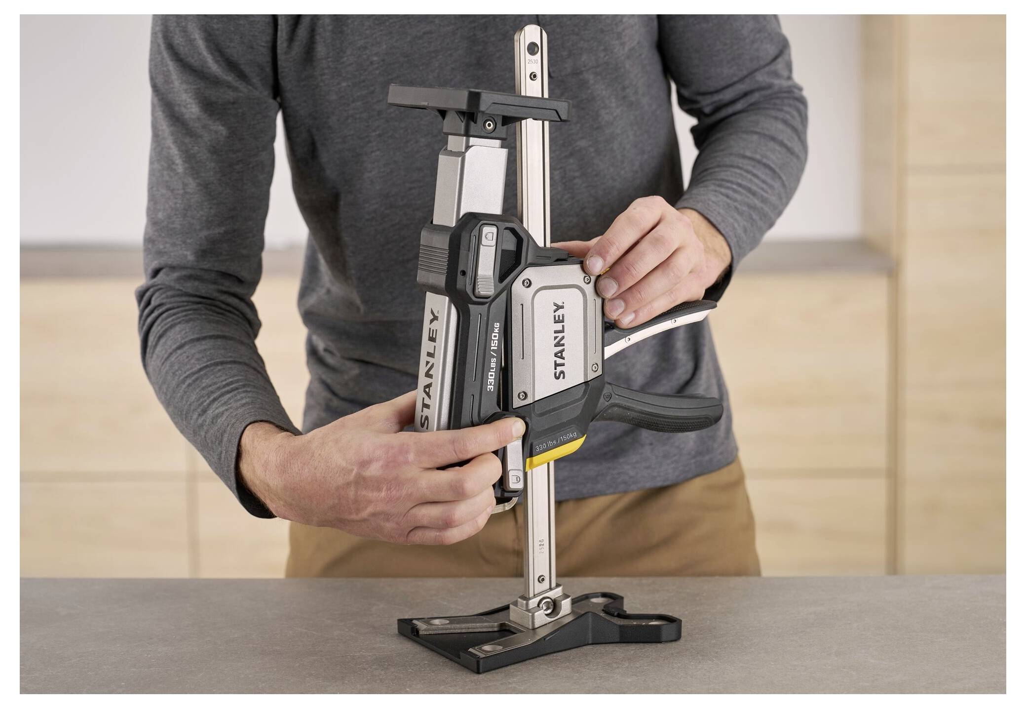 Eine Person passt eine Stanley-Schraubzwinge für die Holzbearbeitung auf einem Tisch an und demonstriert ihre Merkmale und Funktionalität.