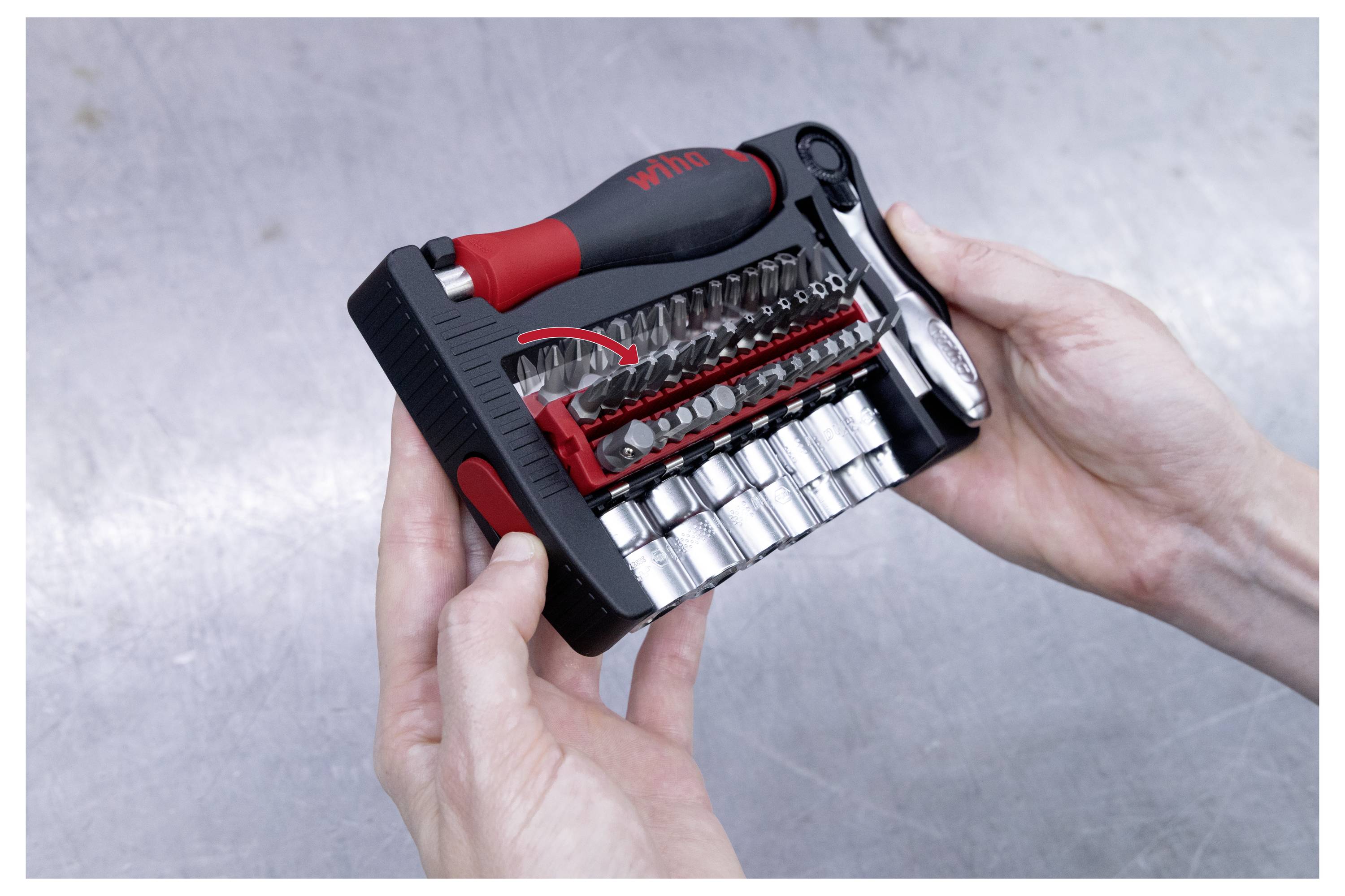 „Hände, die einen kompakten schwarzen und roten Werkzeugsatz mit verschiedenen Schraubendreher-Bits und Stecknüssen halten, gekennzeichnet als Wiha.
