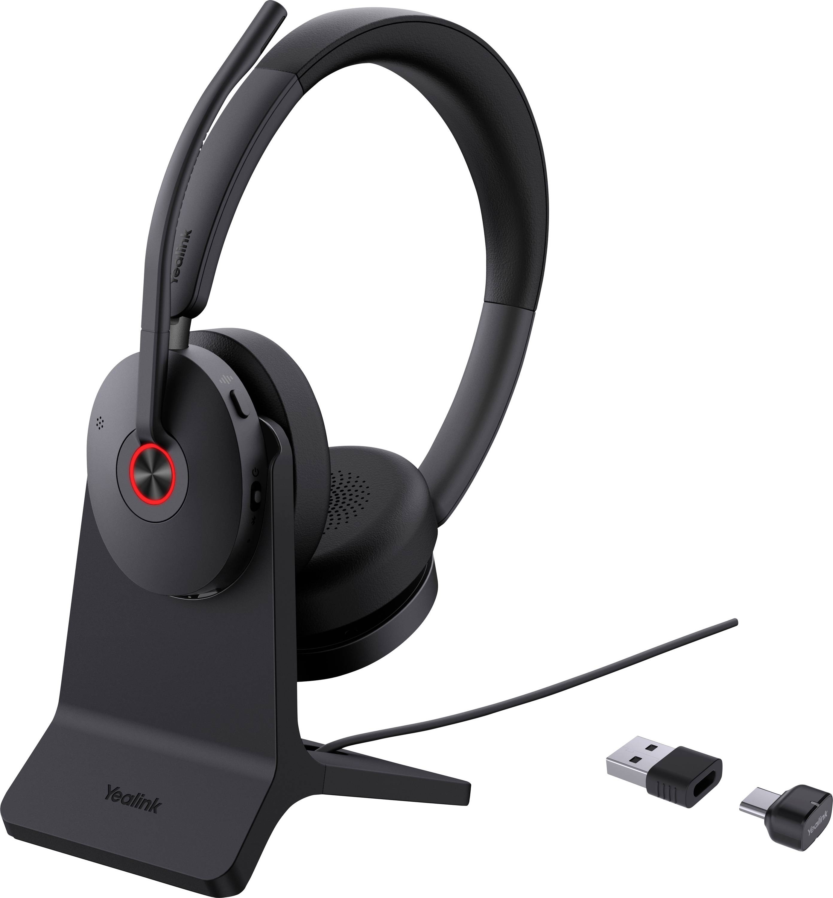 Ein schwarzes kabelloses Headset mit Mikrofon auf einer Ladestation, begleitet von einem USB-Adapter und Stecker, geeignet für die Verwendung am Computer.