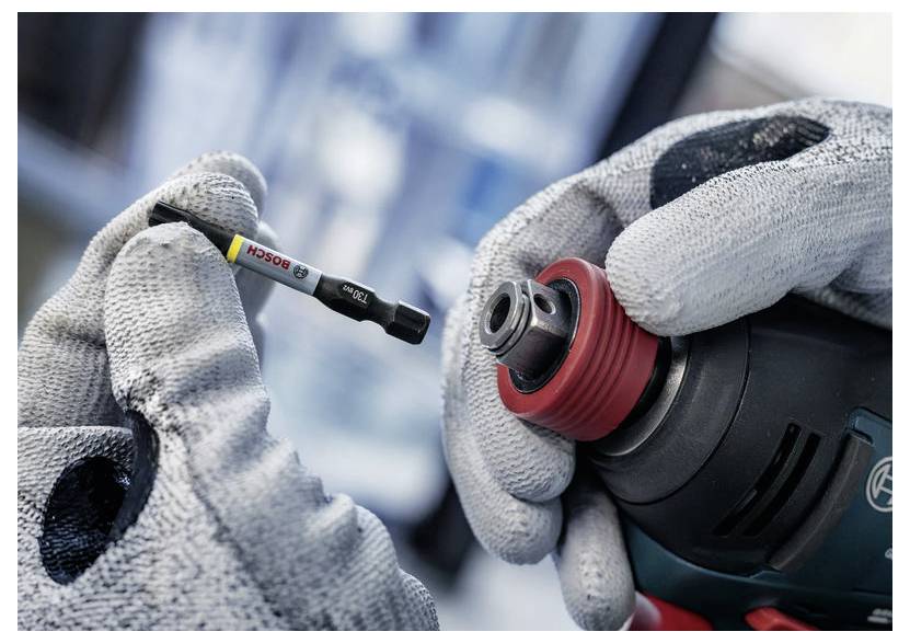 Eine Person mit Handschuhen hält einen Elektrobohrer und einen Bohraufsatz mit einem „Bosch