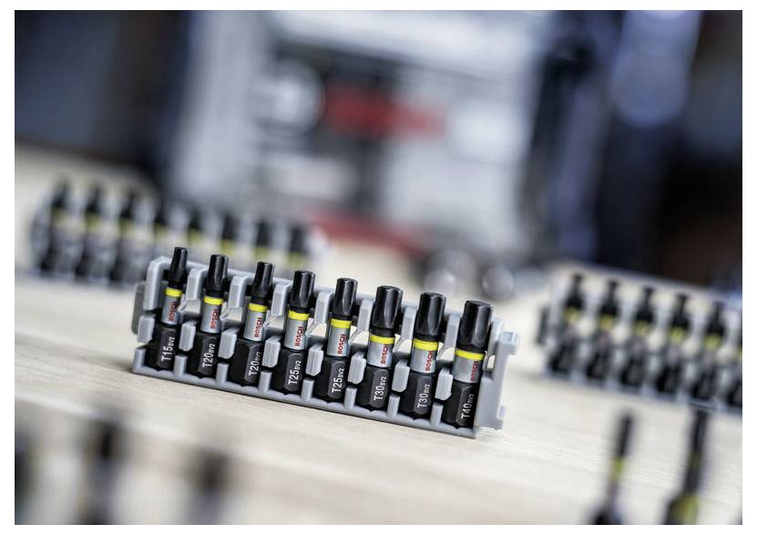 Eine Reihe kleiner, ordnungsgemäß angeordneter schwarzer und grauer elektrischer Stecker mit Beschriftungen, auf einer Holzoberfläche positioniert. Unscharfer Hintergrund.