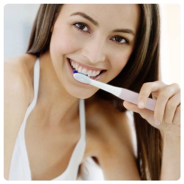 Eine Person, die lächelt und eine elektrische Zahnbürste benutzt.