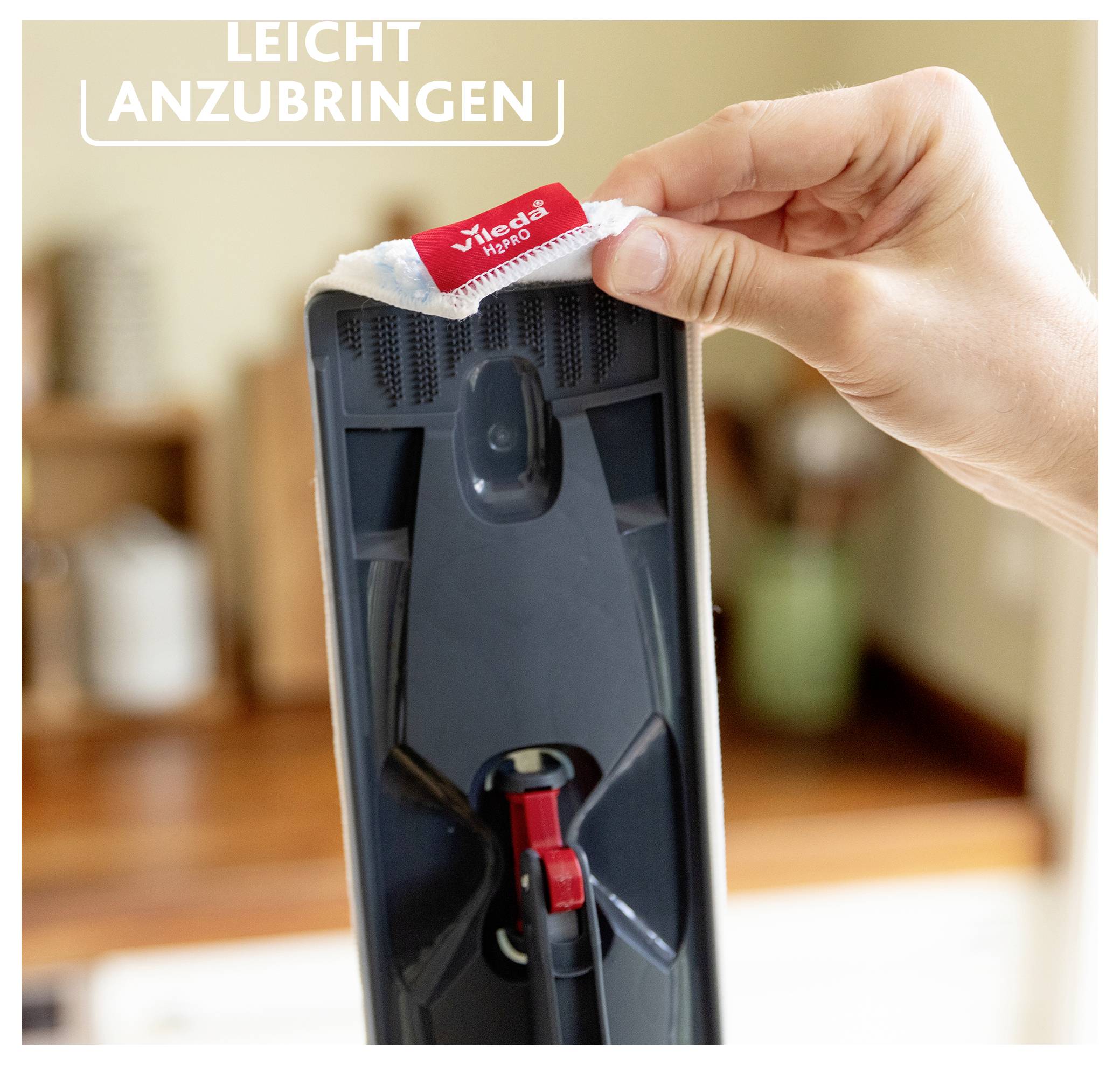 Eine Hand befestigt einen Mop-Ersatz mit der Bezeichnung „Vileda 1-2 Spray