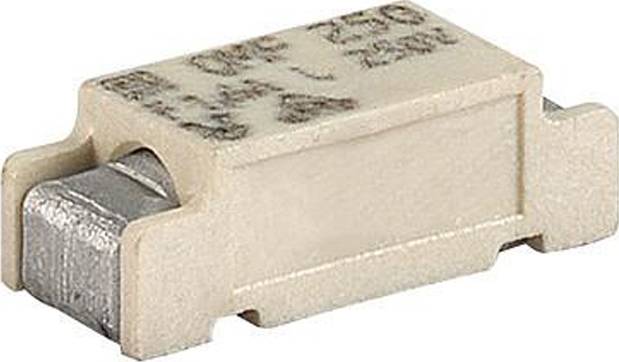 Ein Nahaufnahmebild einer beigen rechteckigen elektronischen Komponente, vermutlich eine SMD-Sicherung, mit metallischen Enden und schwachen Textmarkierungen.