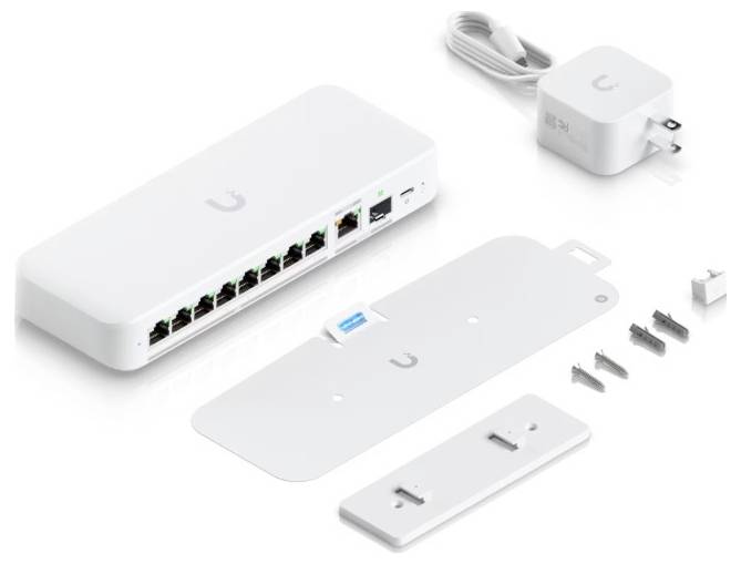 „Ubiquiti-Netzwerk-Switch mit mehreren Ethernet-Anschlüssen, Netzteil, Befestigungswinkel, Schrauben und Zubehör, angeordnet auf weißer Oberfläche.