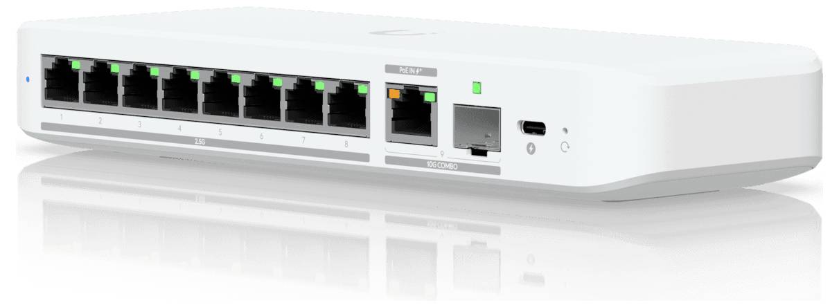 Ein weißer Netzwerk-Switch mit acht Ethernet-Anschlüssen, einem SFP-Anschluss und einem USB-C-Anschluss, beleuchtete Status-LEDs, auf einer reflektierenden Oberfläche.
