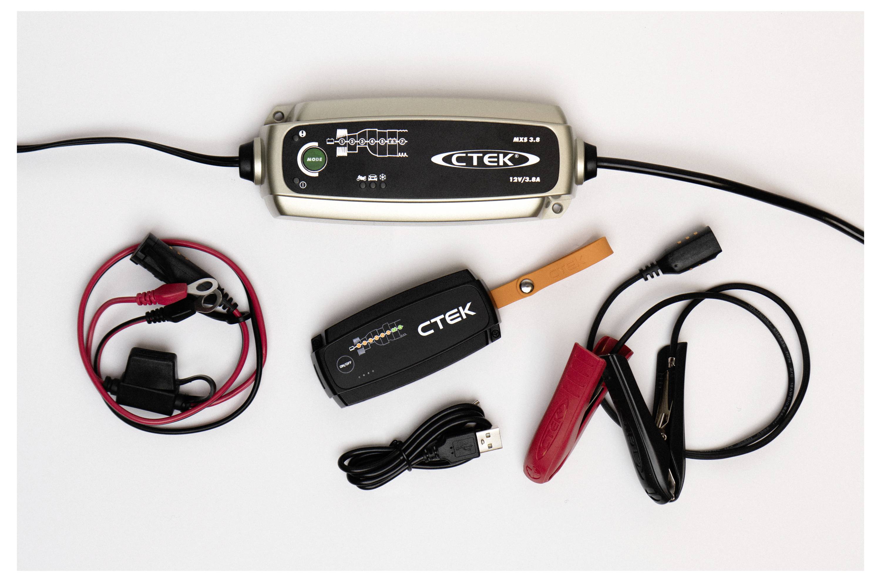 Ein Batterie-Ladegerät-Set mit Hauptgerät, Krokodilklemmen und USB-Kabel auf einer weißen Oberfläche.