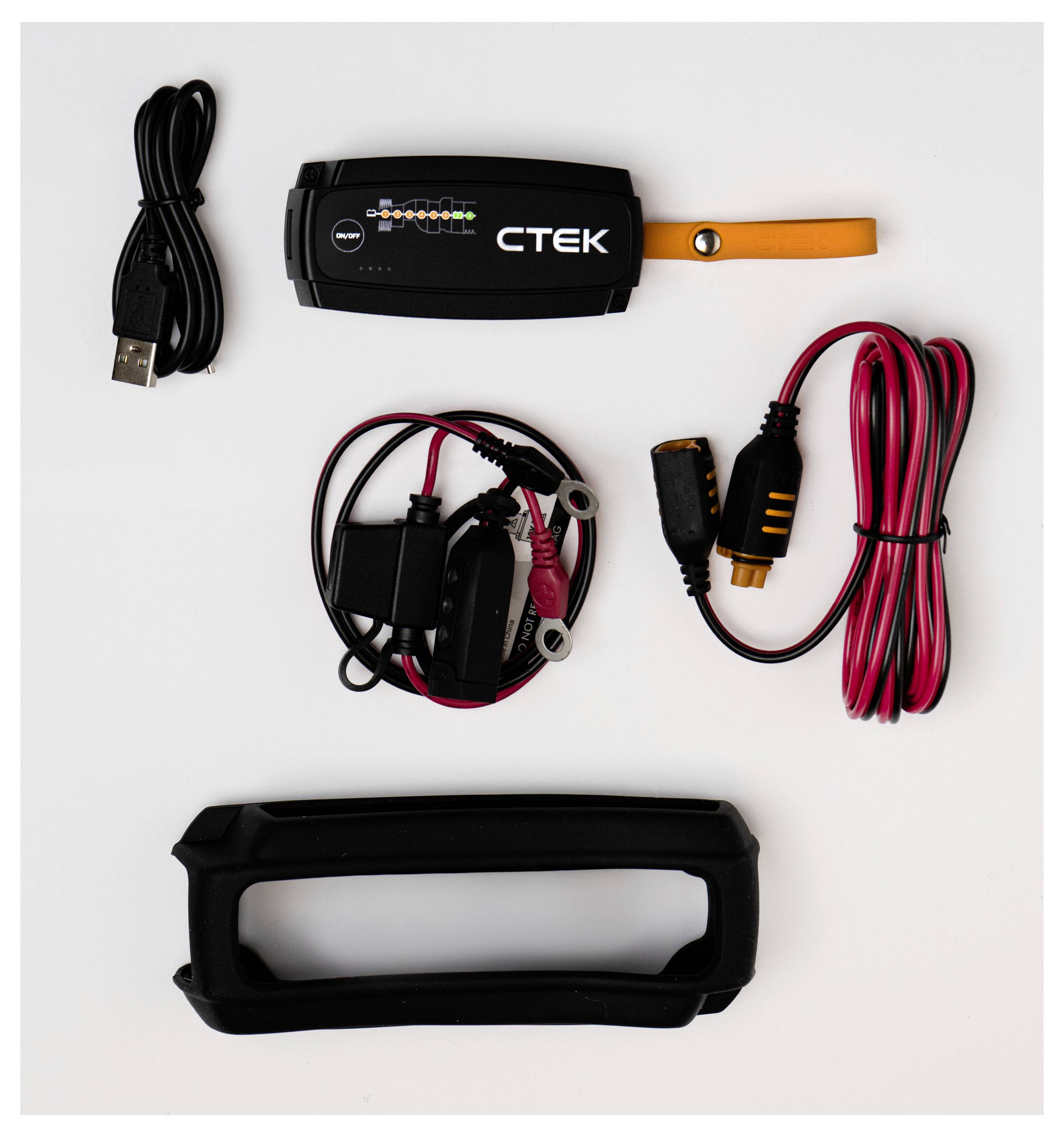 CTEK-Batterieladegerät-Set mit Hauptgerät, USB-Kabel, Ladekabeln und einer Schutzhülle, angeordnet auf einer weißen Oberfläche.
