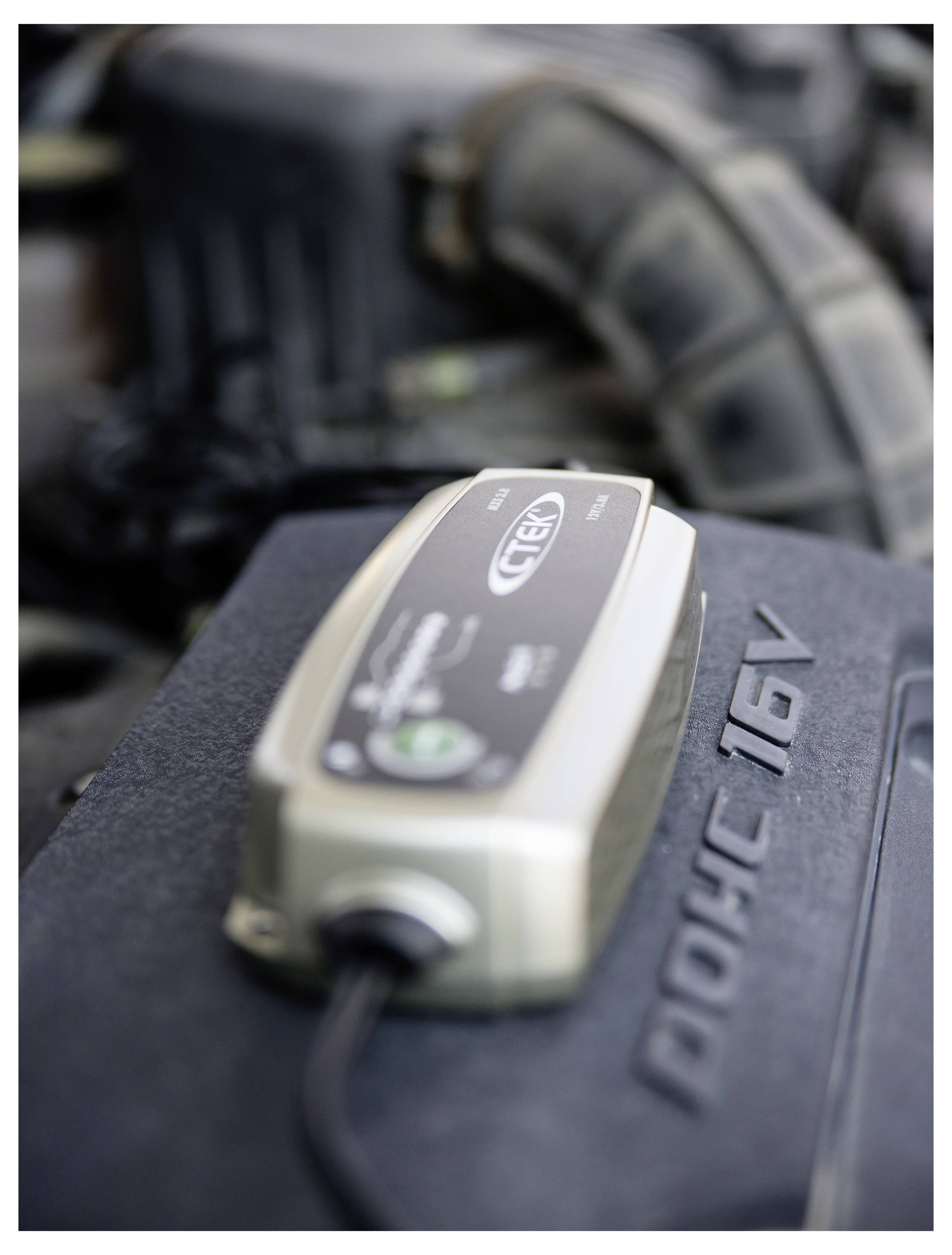 Ein Batterieladegerät, das mit einem Automotor verbunden ist und die Batteriewartung oder den laufenden Ladevorgang anzeigt.