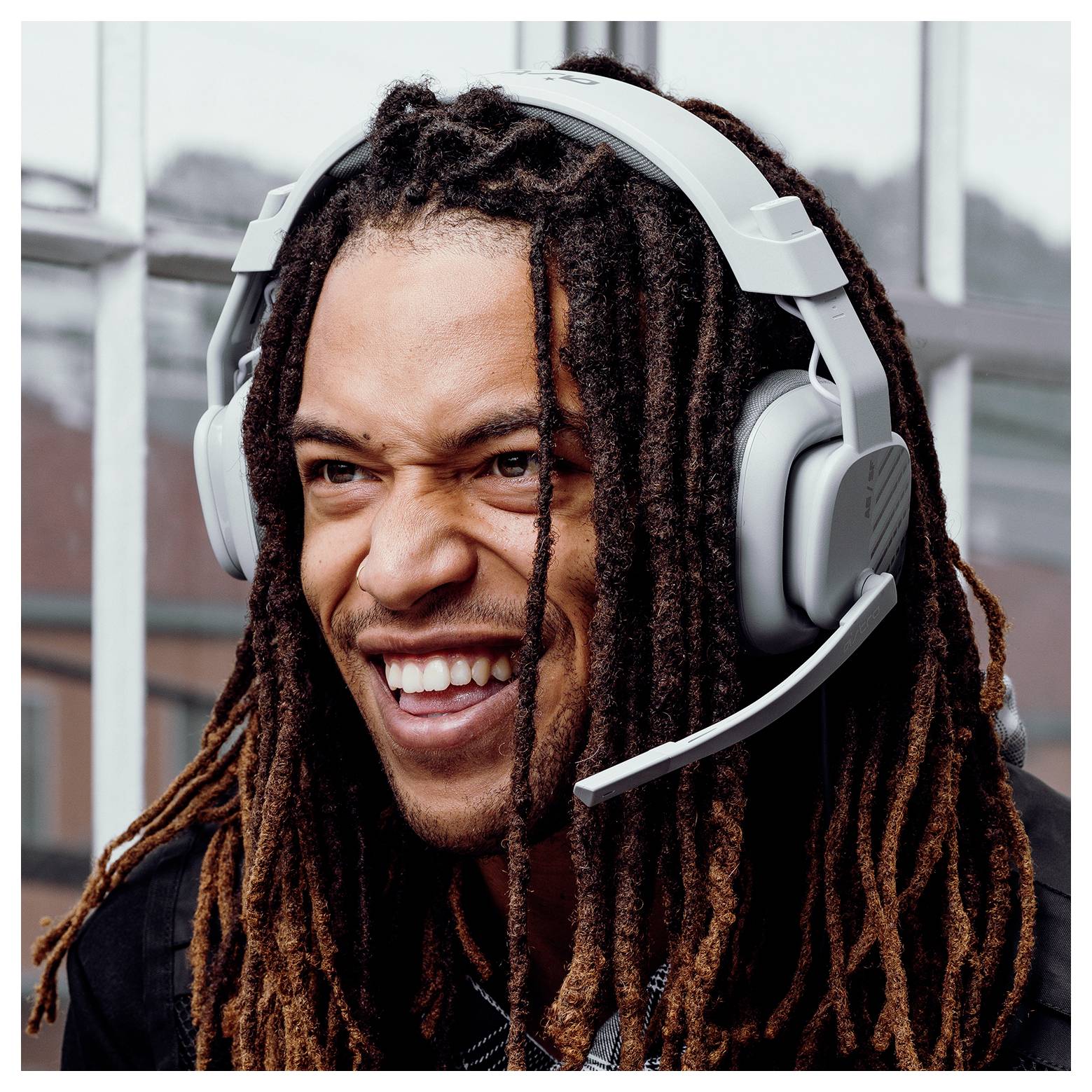Nahaufnahme eines lächelnden Mannes mit langen Dreadlocks, der ein Gaming-Headset mit Mikrofon trägt.