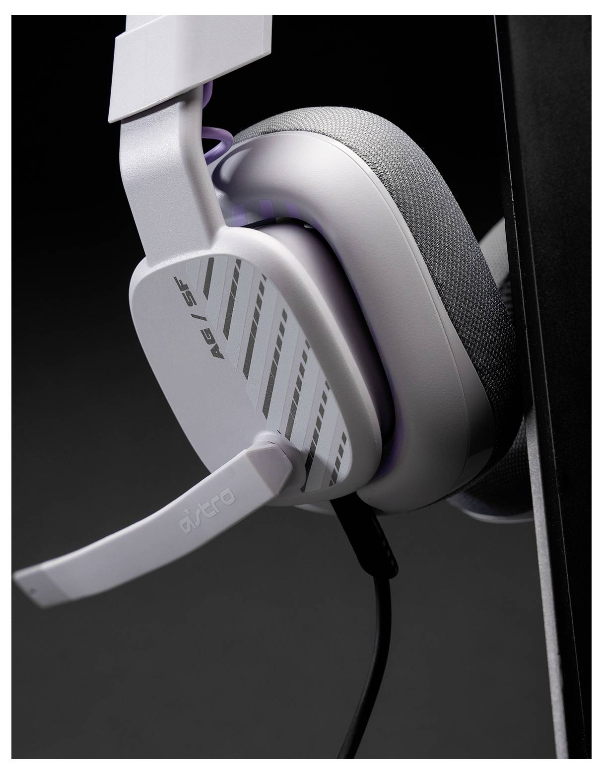 Nahaufnahme eines weißen und grauen Over-Ear-Gaming-Kopfhörers mit Boom-Mikrofon, das vor einem dunklen Hintergrund hängt.
