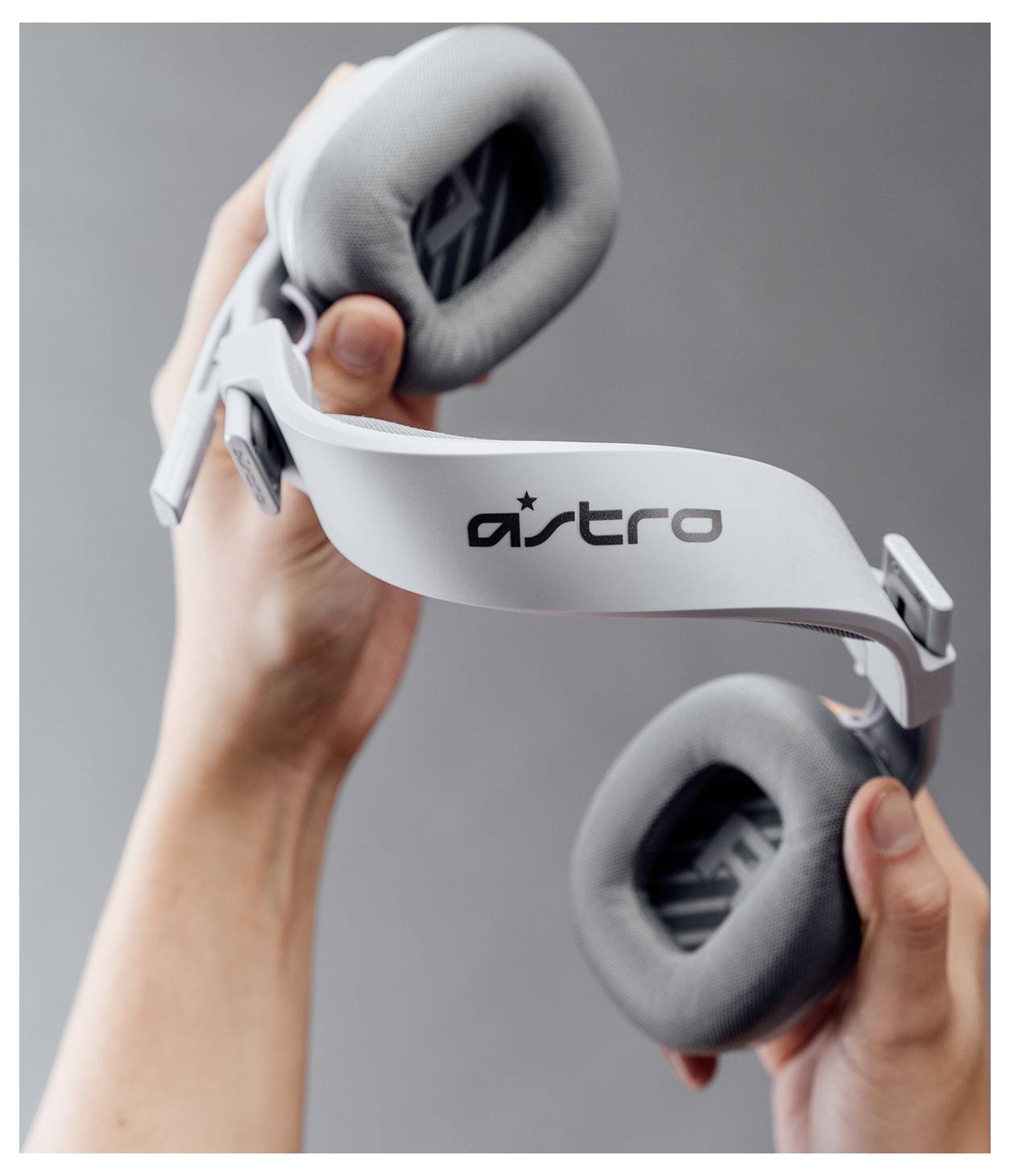 Hände halten Astro Over-Ear-Kopfhörer-Ohrmuscheln und Kopfbügel vor einem grauen Hintergrund.