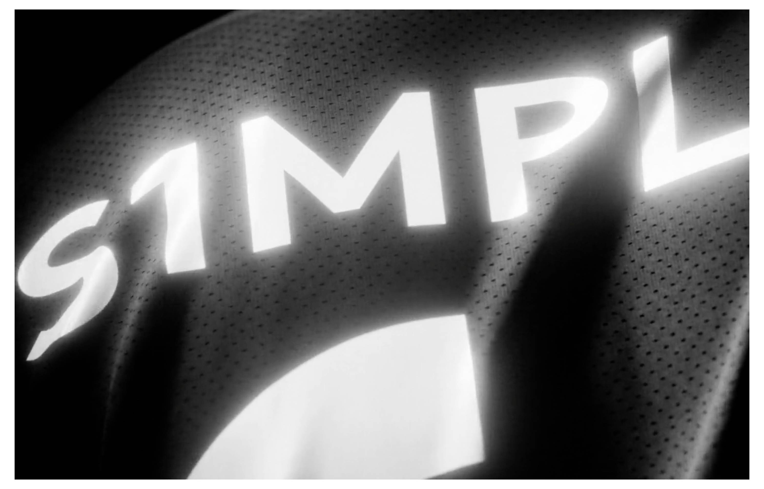 Nahaufnahme eines schwarzen Sporttrikots mit großen weißen Buchstaben „SIMP