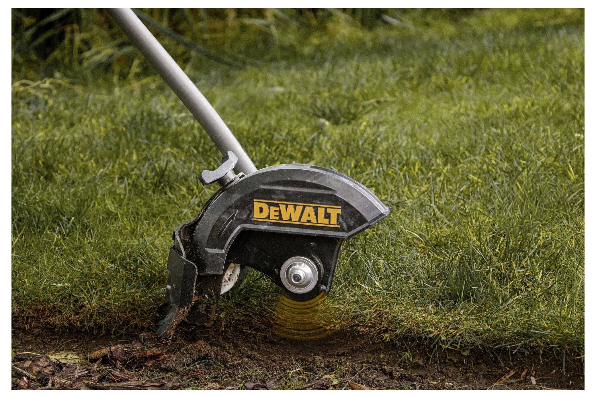 Ein Rasenkantenschneider schneidet Gras entlang einer Gartenkante und schafft so eine saubere Grenze zwischen Gras und Boden.