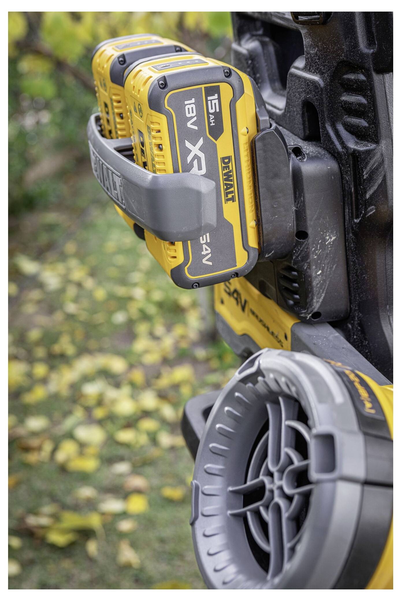 Eine Stromwerkzeug-Batterieeinheit mit mehreren angebrachten gelben Batterien, auf der Markenlogos zu sehen sind. Im Hintergrund gelbe Blätter auf dem Boden.