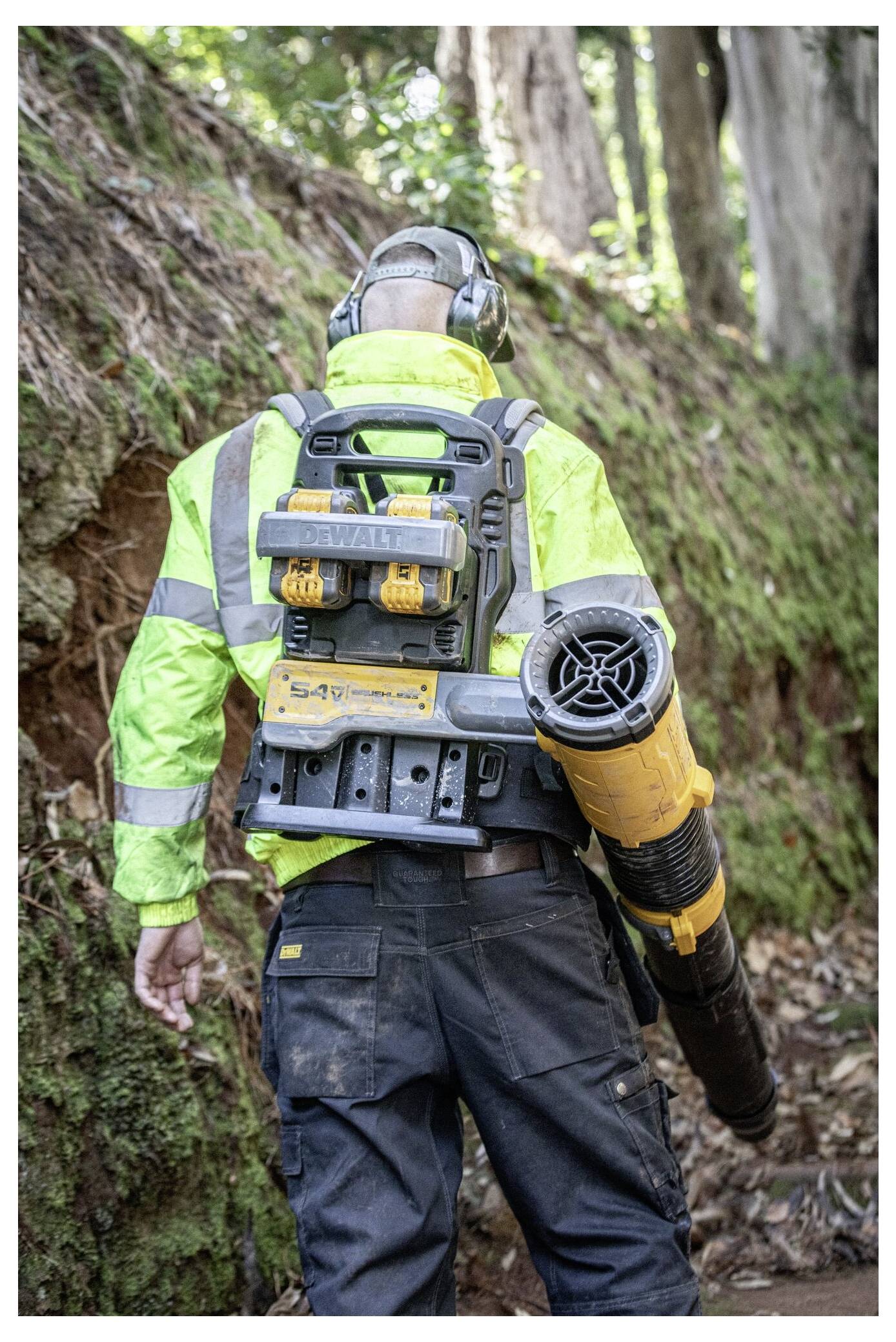 Ein Mann benutzt einen Hochdruckreiniger, um einen Außensteinweg an einem bewölkten Tag zu reinigen, wobei er eine Schutzbrille und Handschuhe trägt.