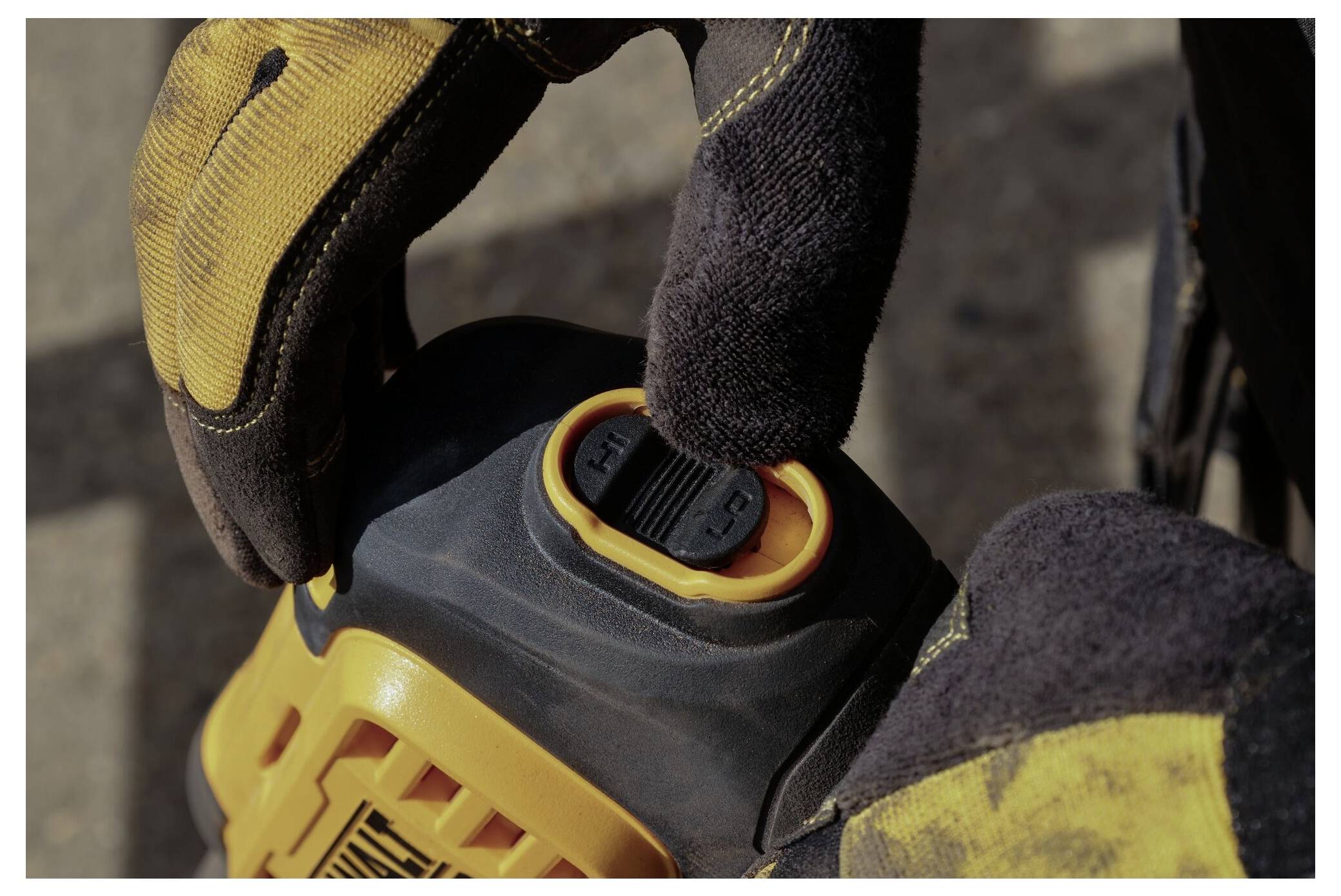 Eine Person mit Handschuhen hält ein Metallschneidewerkzeug neben einem gelben Elektrowerkzeug, möglicherweise einer Oberfräse, auf einer Werkbank mit Schrauben in der Nähe.