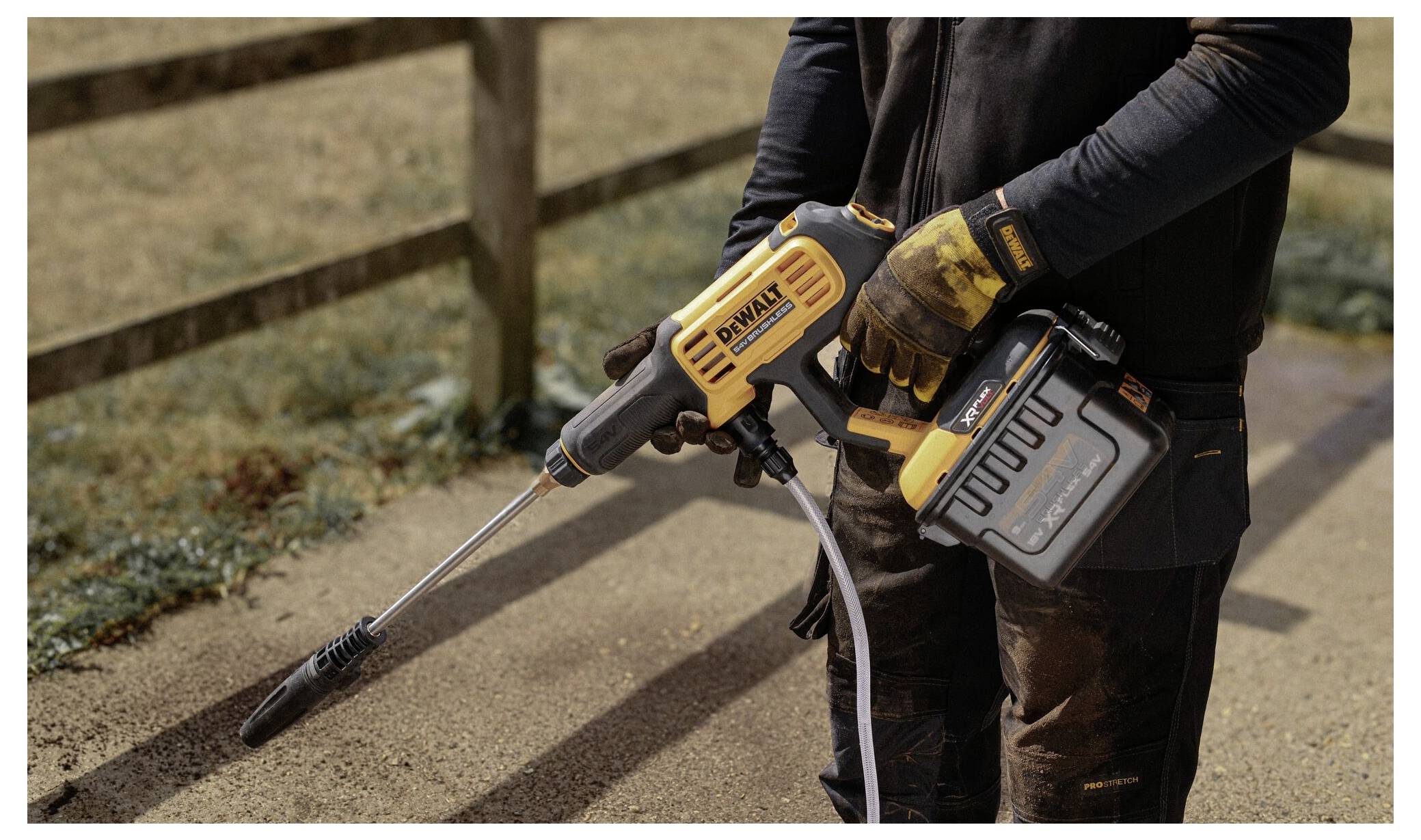 Ein Bauarbeiter mit Helm und Warnweste steht neben einer Gehrungssäge auf einer Holzplanke auf einer Baustelle im Innenbereich.