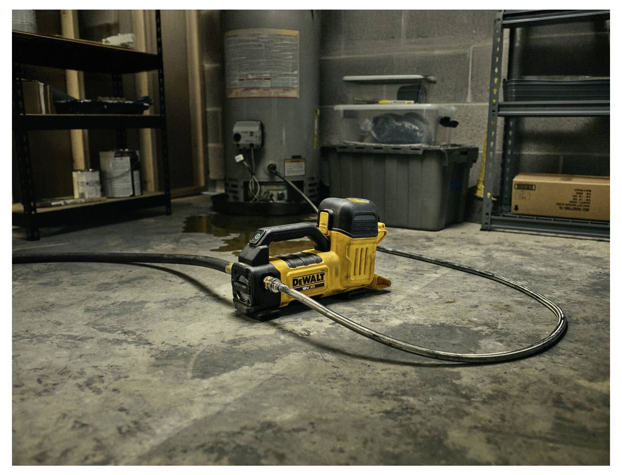 Ein gelber tragbarer Luftkompressor mit einem Schlauch liegt auf einem Betonboden in einer Garage, umgeben von Regalen und Lagerbehältern.