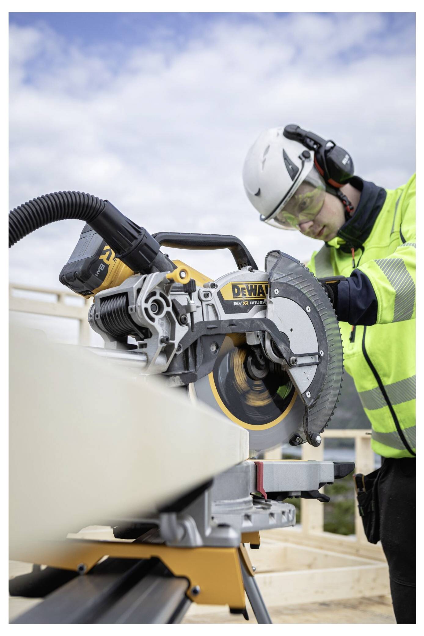 Ein Bauarbeiter, der persönliche Schutzausrüstung trägt, bedient eine Kreissäge auf einer Baustelle.