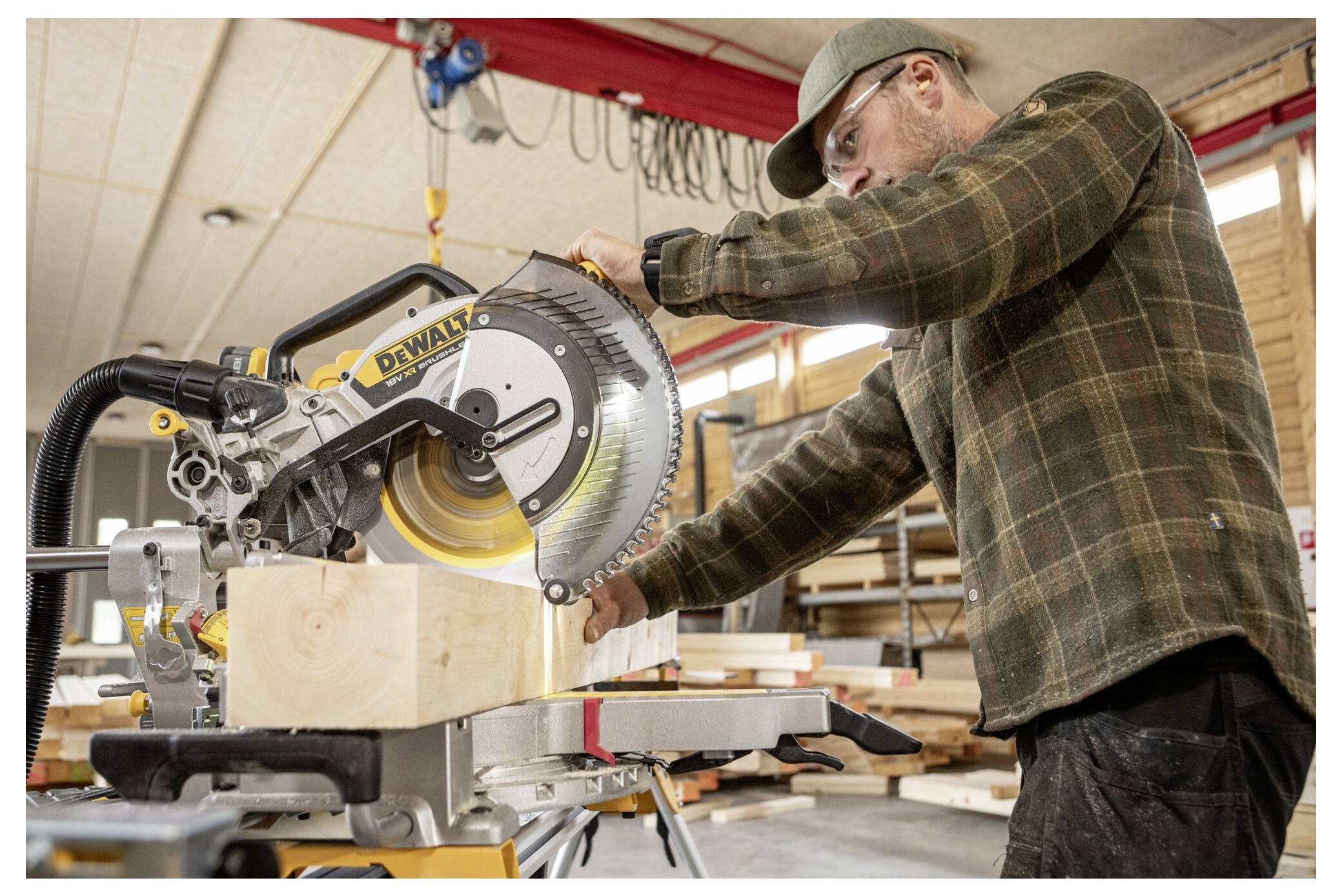 Eine Person, die eine Schutzbrille und Handschuhe trägt, verlegt Dachziegel neben einem Fenster und verwendet ein Universalmesser, um das Unterlagsmaterial zu schneiden.