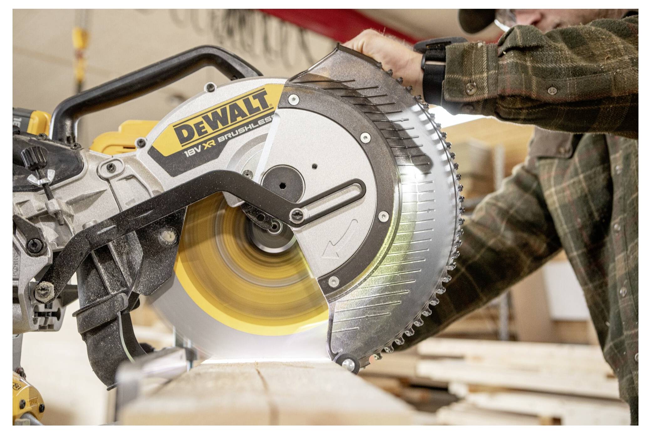 Eine Person in einer Werkstatt schneidet Holz mit einer DeWalt-Kreissäge. Das Sägeblatt dreht sich, und Holzstaub ist sichtbar, was darauf hinweist, dass aktiv geschnitten wird.